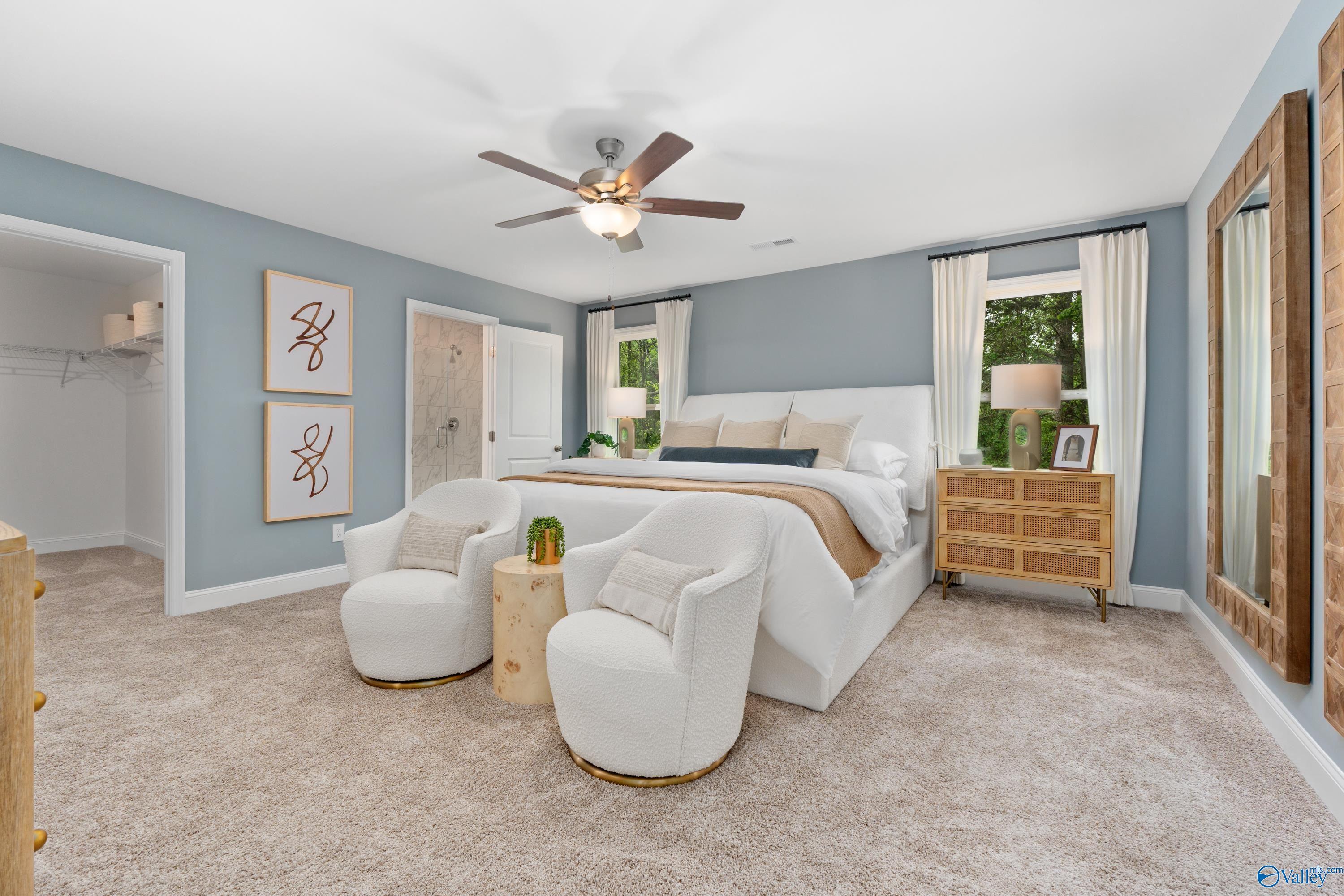 Elegant master bedroom with king bed, white swivel chairs, ceiling fan, and natural light in The Camden, Davidson Homes, Huntsville AL