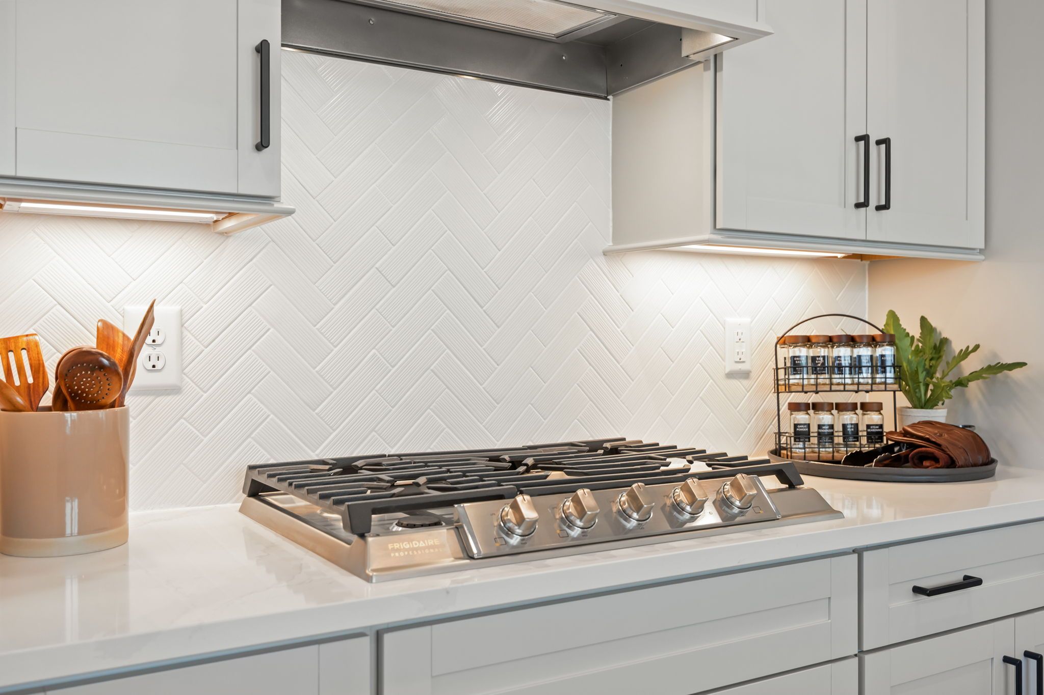 Modern kitchen in Camden Park, Knightdale NC with white shaker cabinets, herringbone subway tile backsplash, and gas range