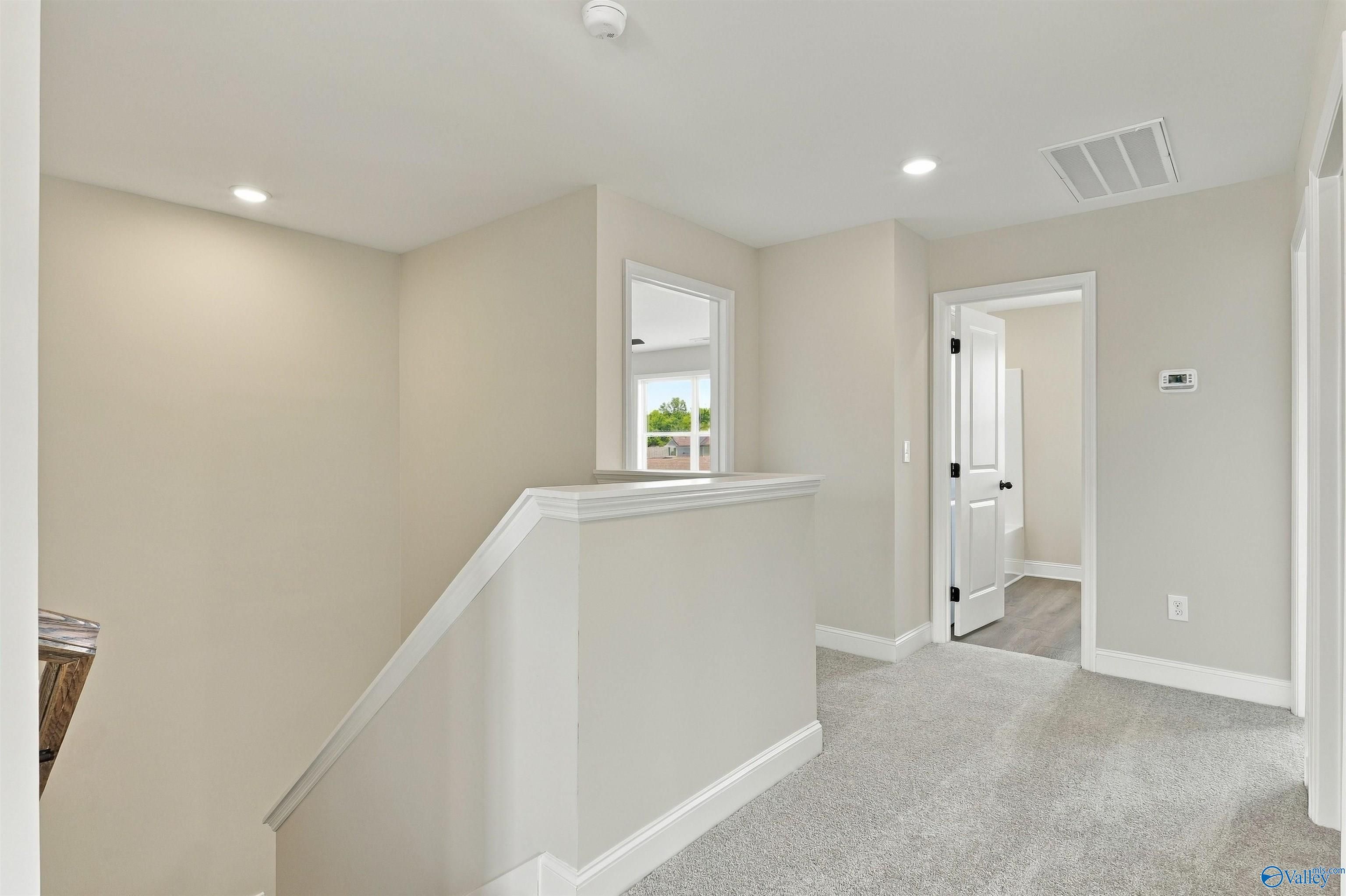 Bright carpeted upstairs loft with staircase overlooking lower level in Davidson Homes The Shelby A, The Meadows, Athens, Alabama