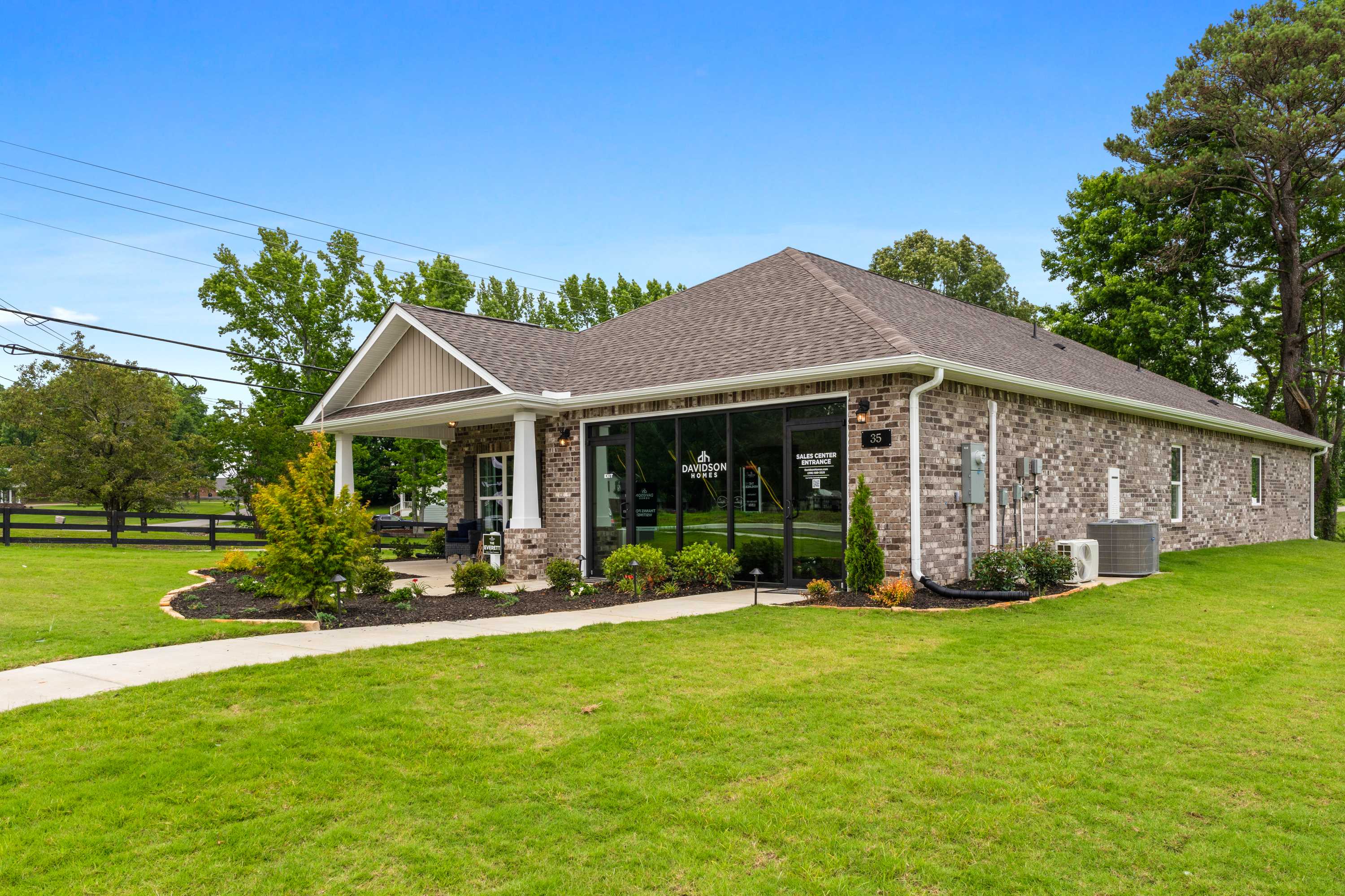 Stone and brick clubhouse at The Highlands in Arab, Alabama with covered porch, large windows, and lush landscaping