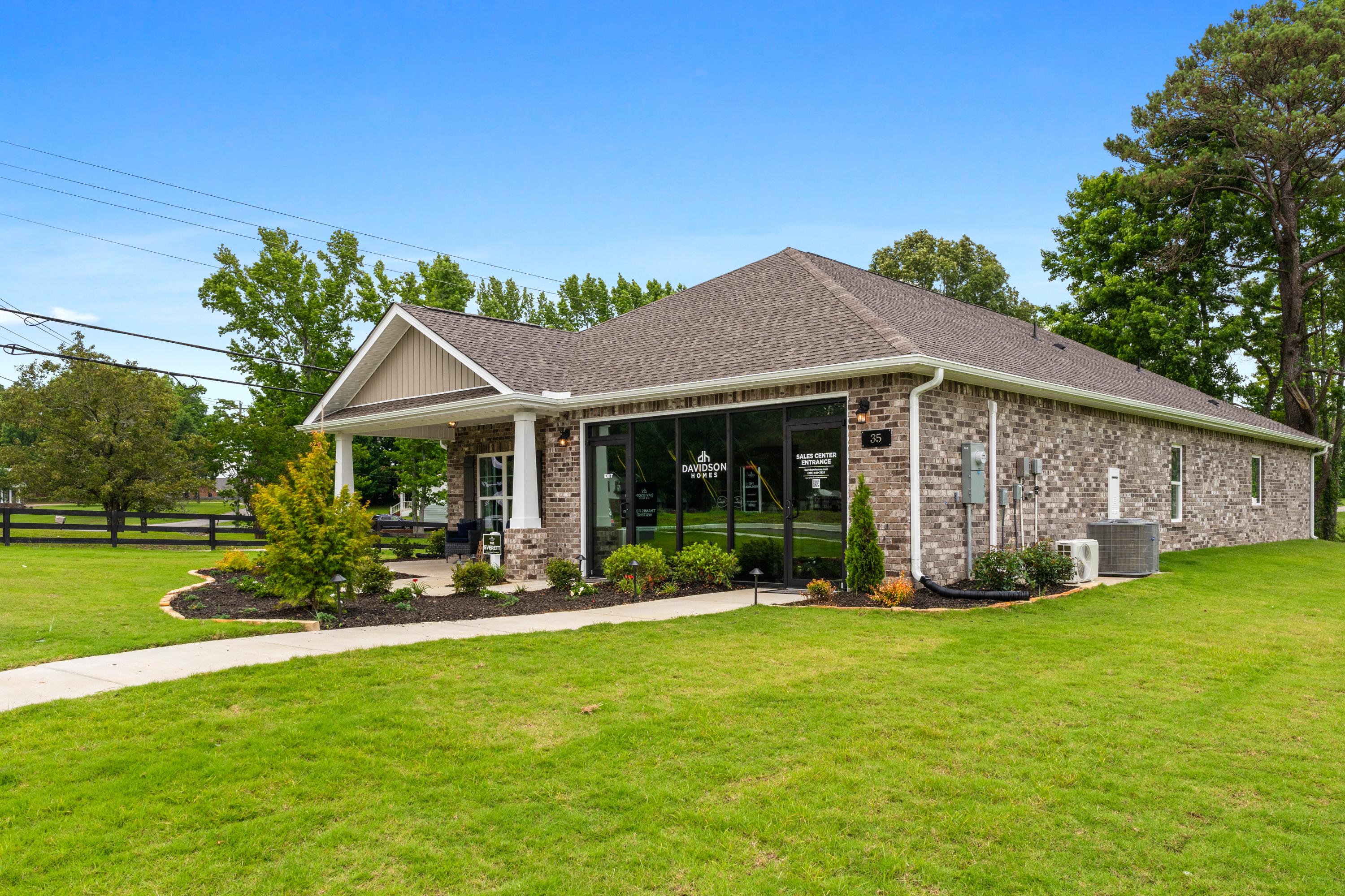 Stone and brick clubhouse at The Highlands in Arab, Alabama with covered porch, large windows, and lush landscaping