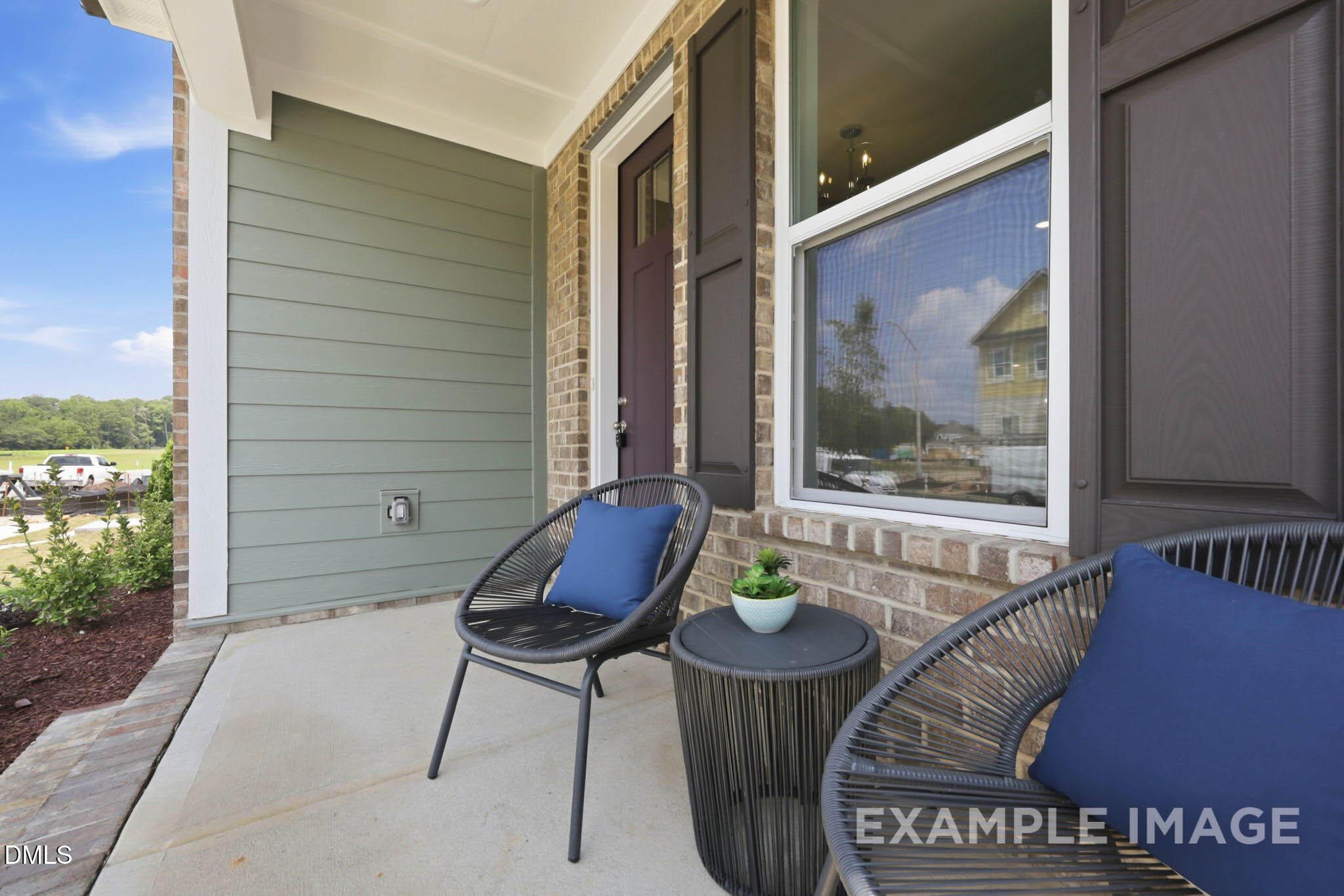 Front porch with wicker seating and blue cushions at Davidson Homes The Jordan C in Forestville Yard, Knightdale, NC