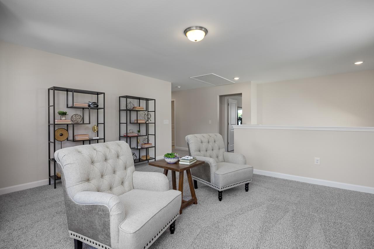 Cozy loft area in The Chestnut featuring tufted armchairs, modern shelving, and neutral decor in a Belmont home.