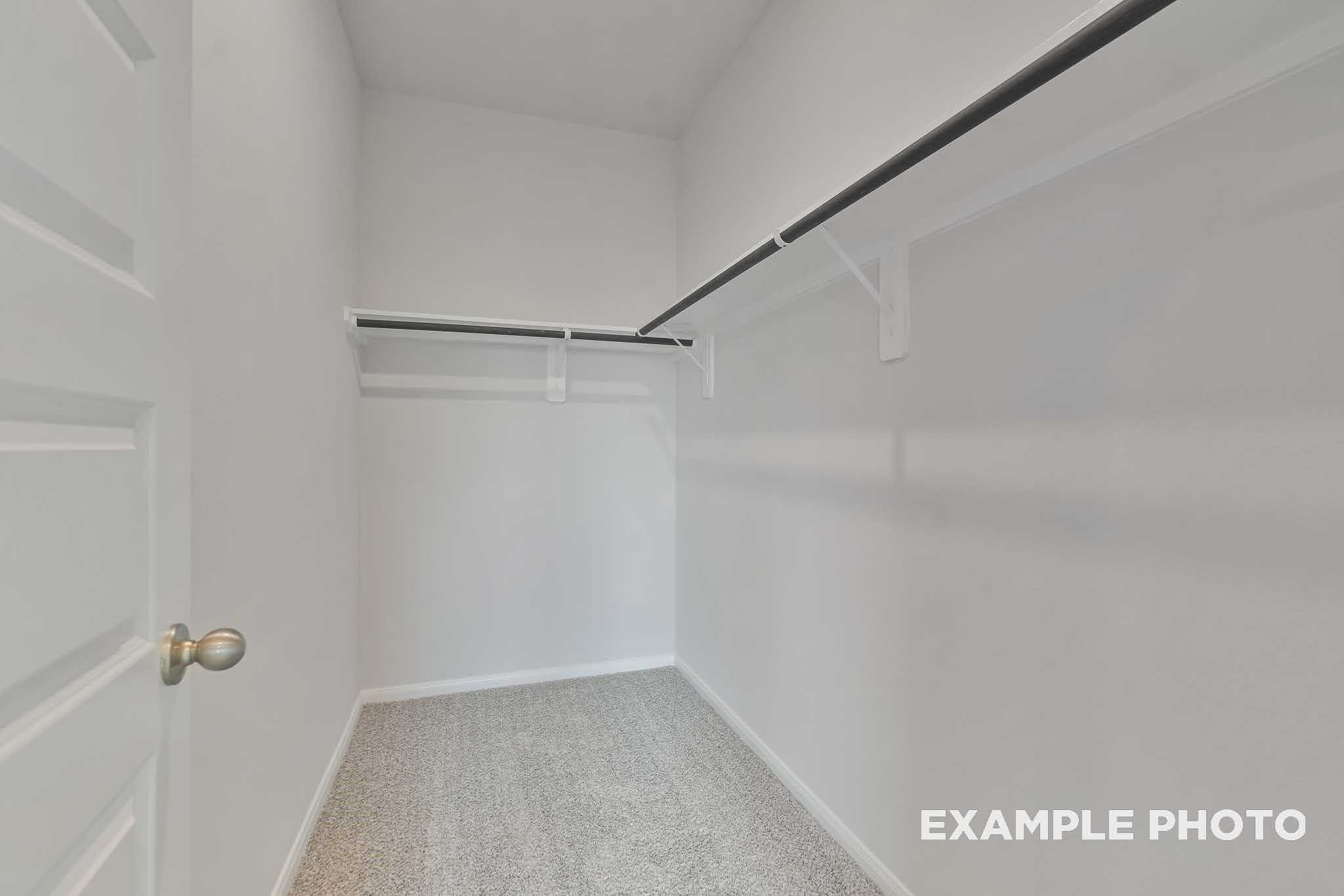 Spacious walk-in closet with double hanging rods and carpet flooring in Davidson Homes The Frio F, Conroe, Texas