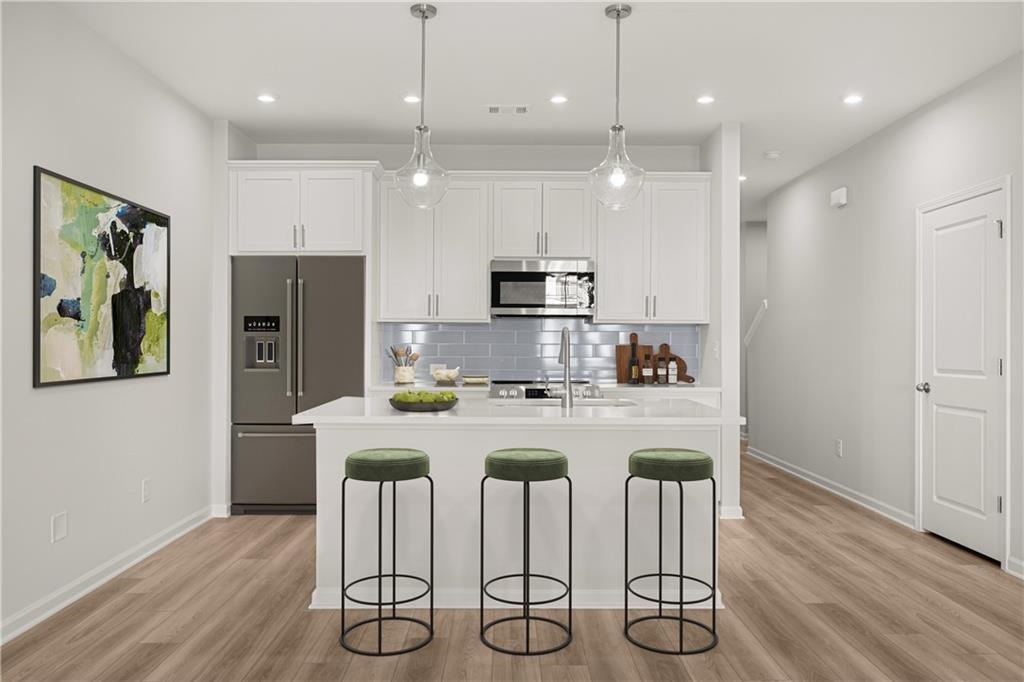 Modern kitchen with white cabinets, island, and seating in The Monroe B floor plan at Stegall Village in Emerson, Georgia.