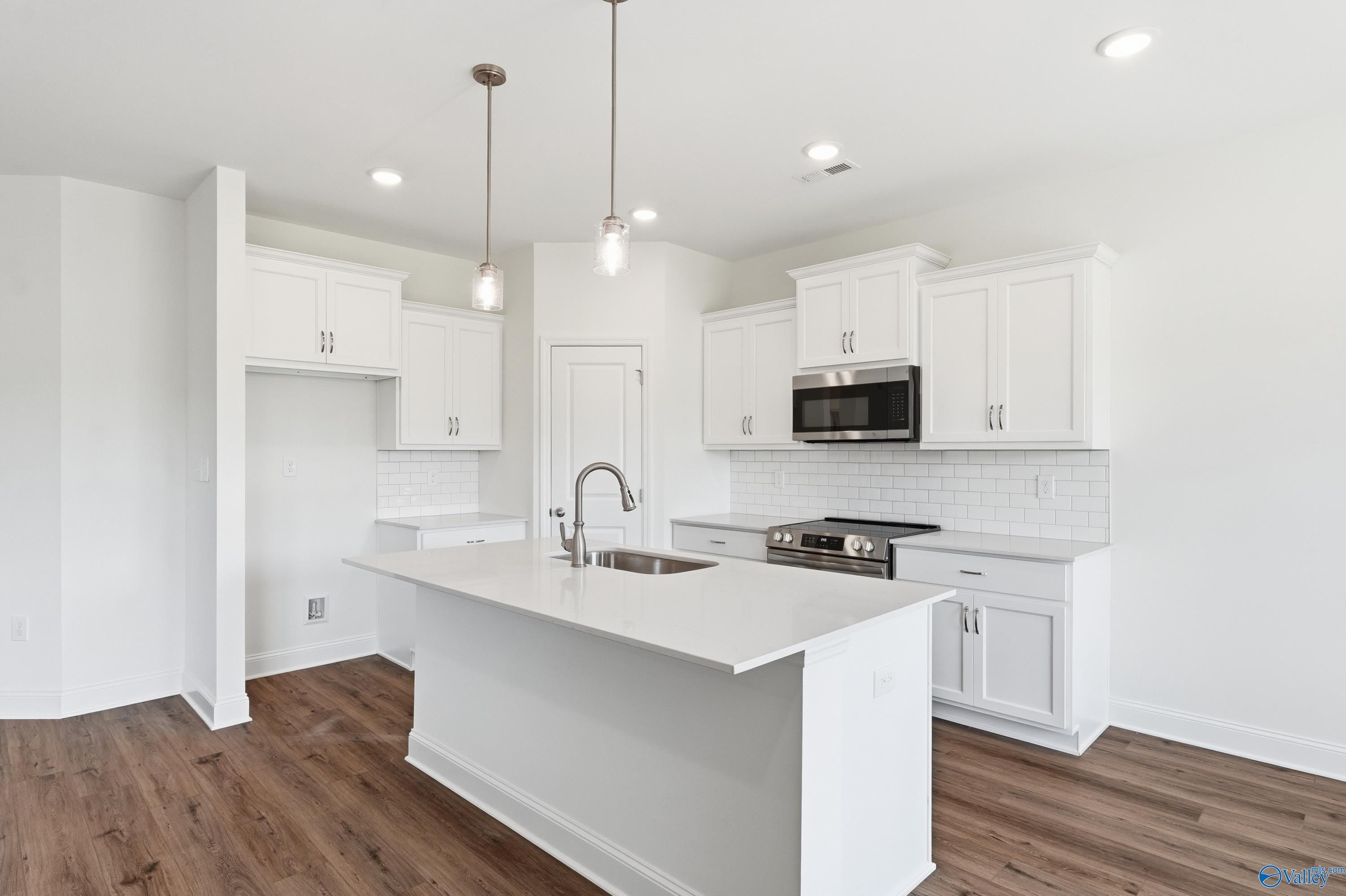 Modern kitchen with a white quartz island, pendant lighting, and stainless steel appliances in The Asheville, Huntsville.