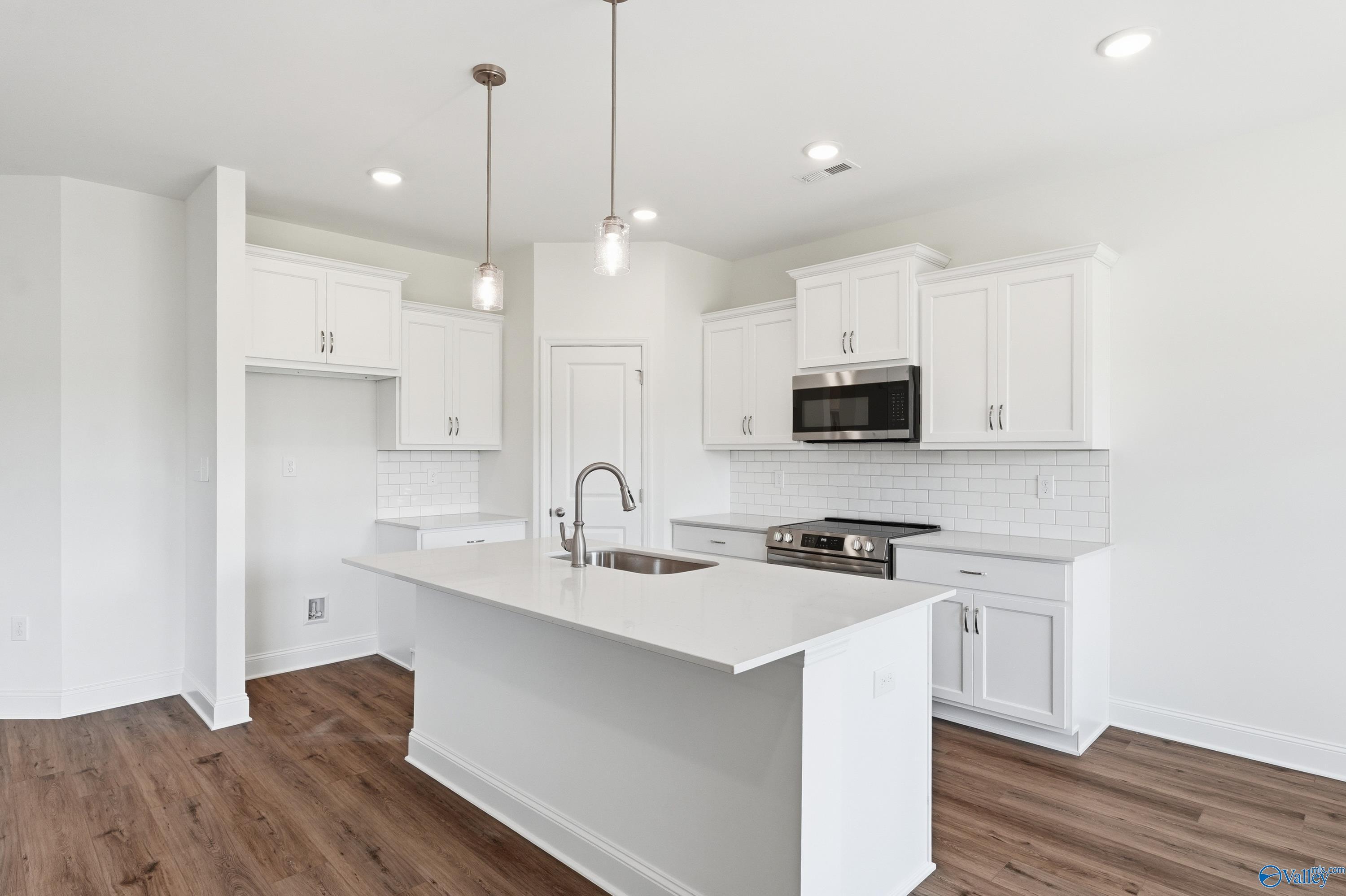 Modern kitchen with a white quartz island, pendant lighting, and stainless steel appliances in The Asheville, Huntsville.