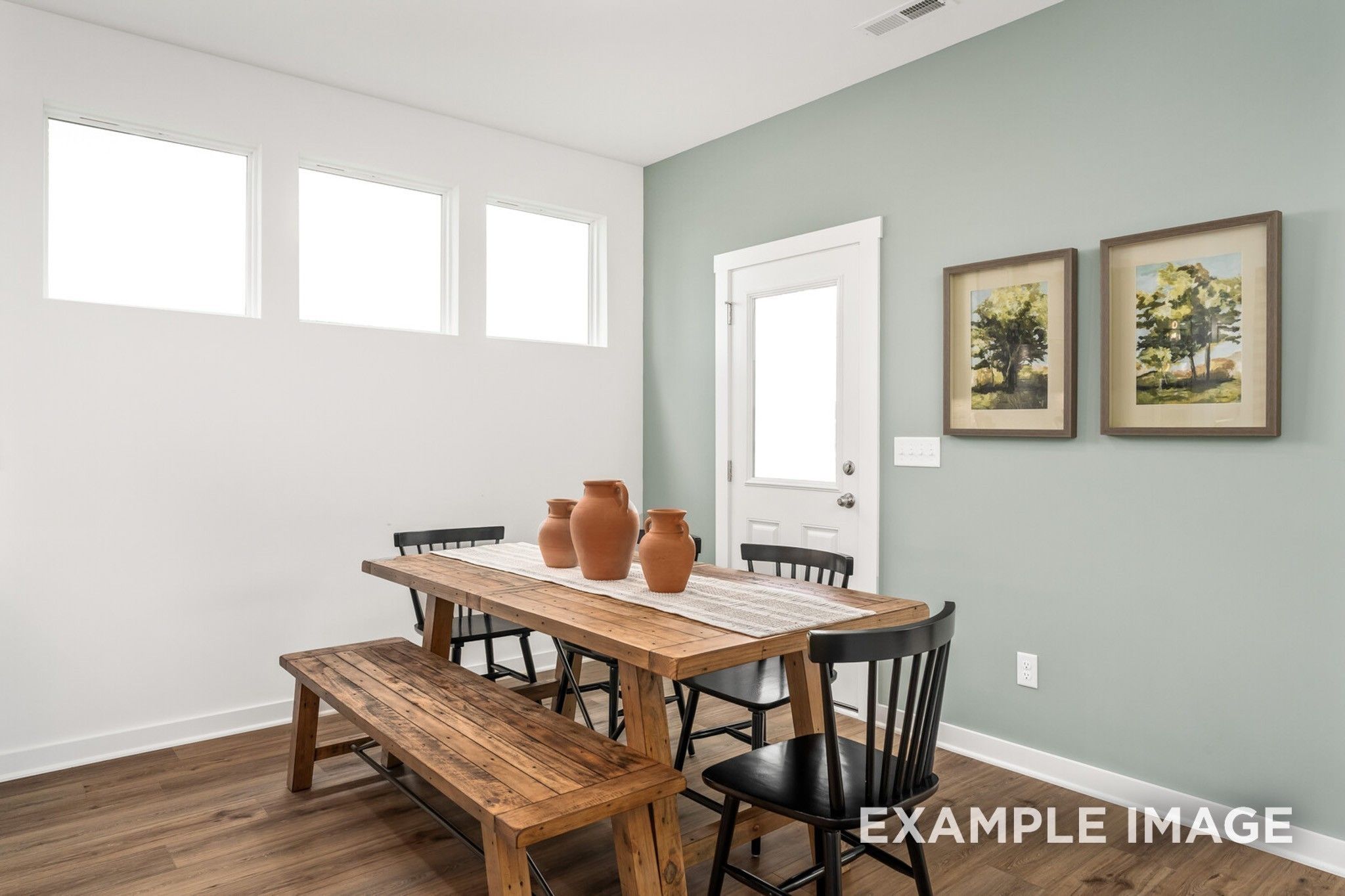 Bright dining area with rustic wood table and bench in The Ash A floor plan at Woods Crossing, Gallatin, Tennessee.