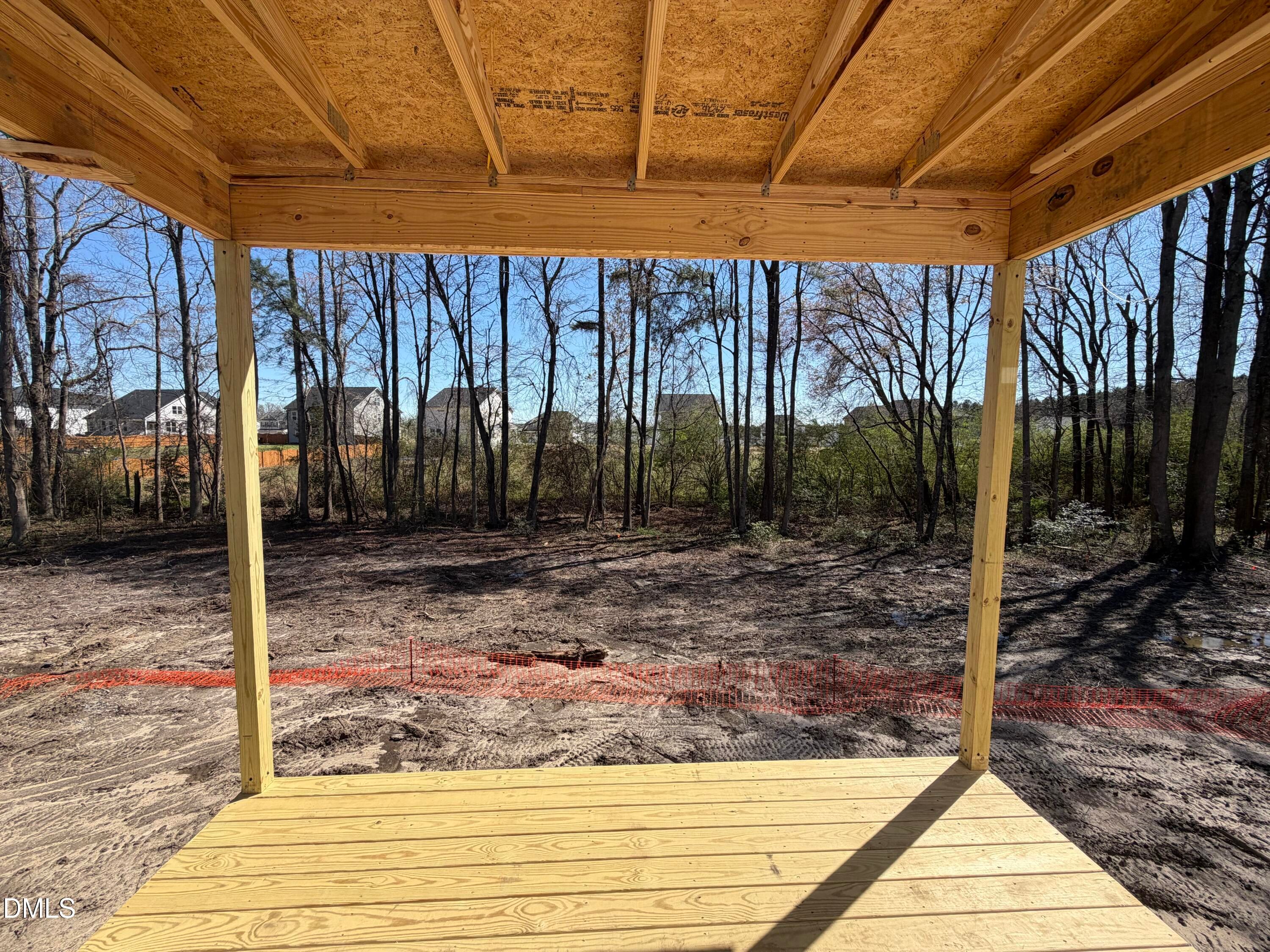 Under-construction covered back patio with wooden frame, plywood roof, and deck overlooking wooded yard in Wellers Knoll, Lillington, NC