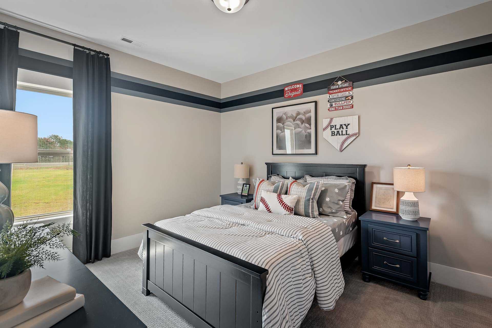 Baseball-themed boy's bedroom at Heritage Lakes in New Market, Alabama with twin bed, sports decor, and window overlooking green field