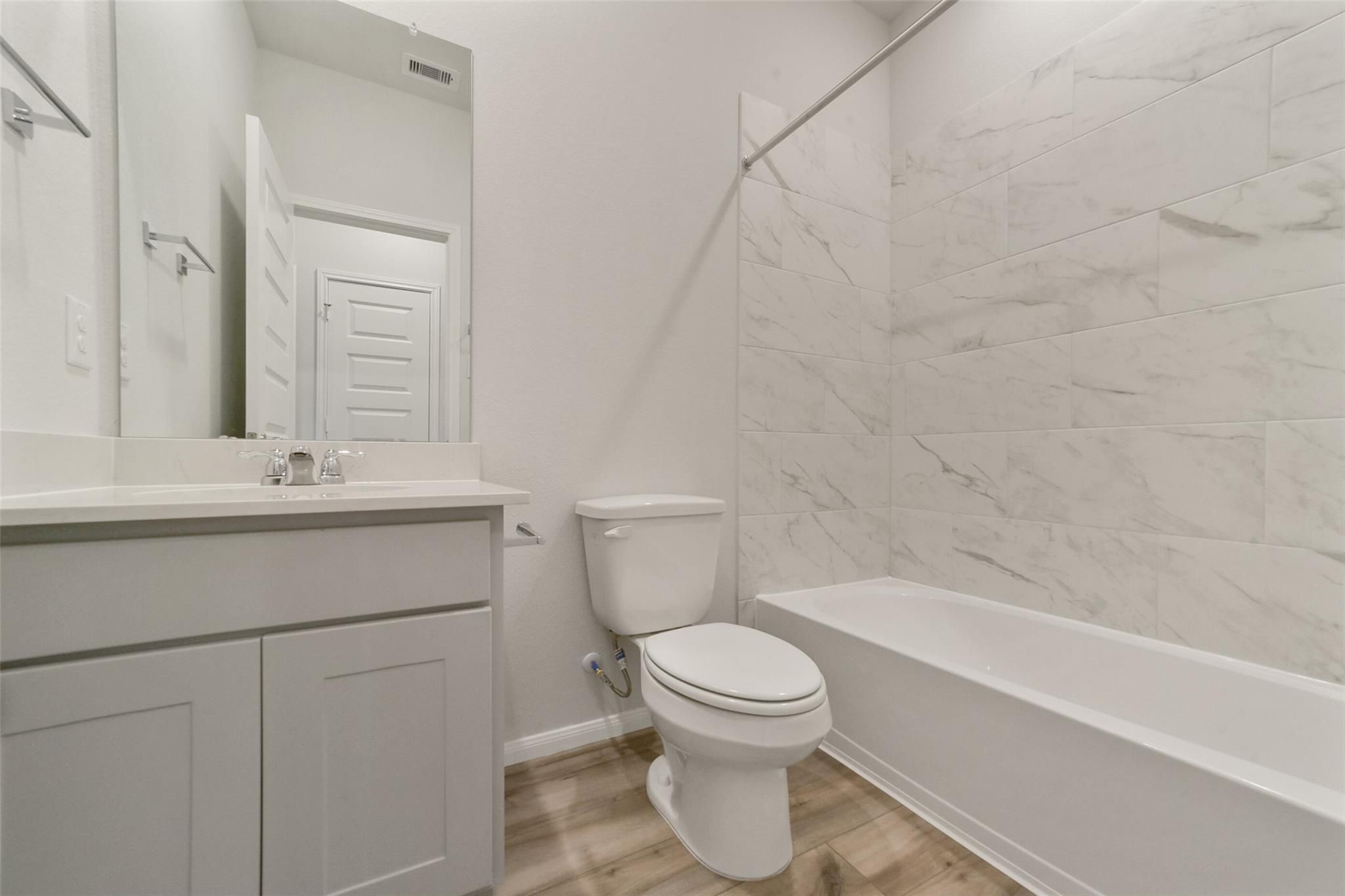 Elegant bathroom with white subway tiles, soaking tub, modern vanity, and toilet in Davidson Homes San Marcos E, Beasley TX
