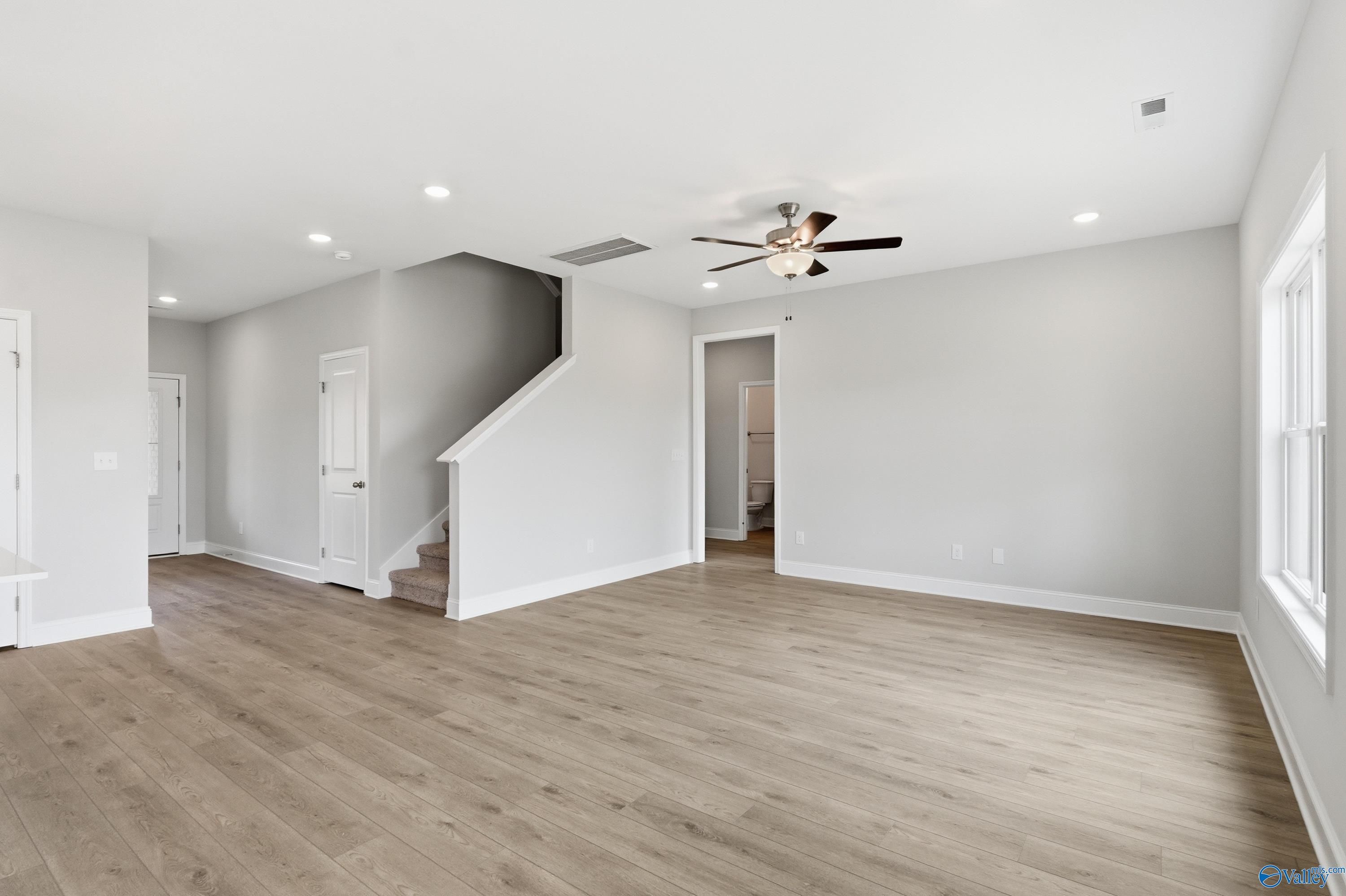 Bright two-story foyer with hardwood floors, ceiling fan, and staircase in Davidson Homes The Shelby B, New Market, Alabama