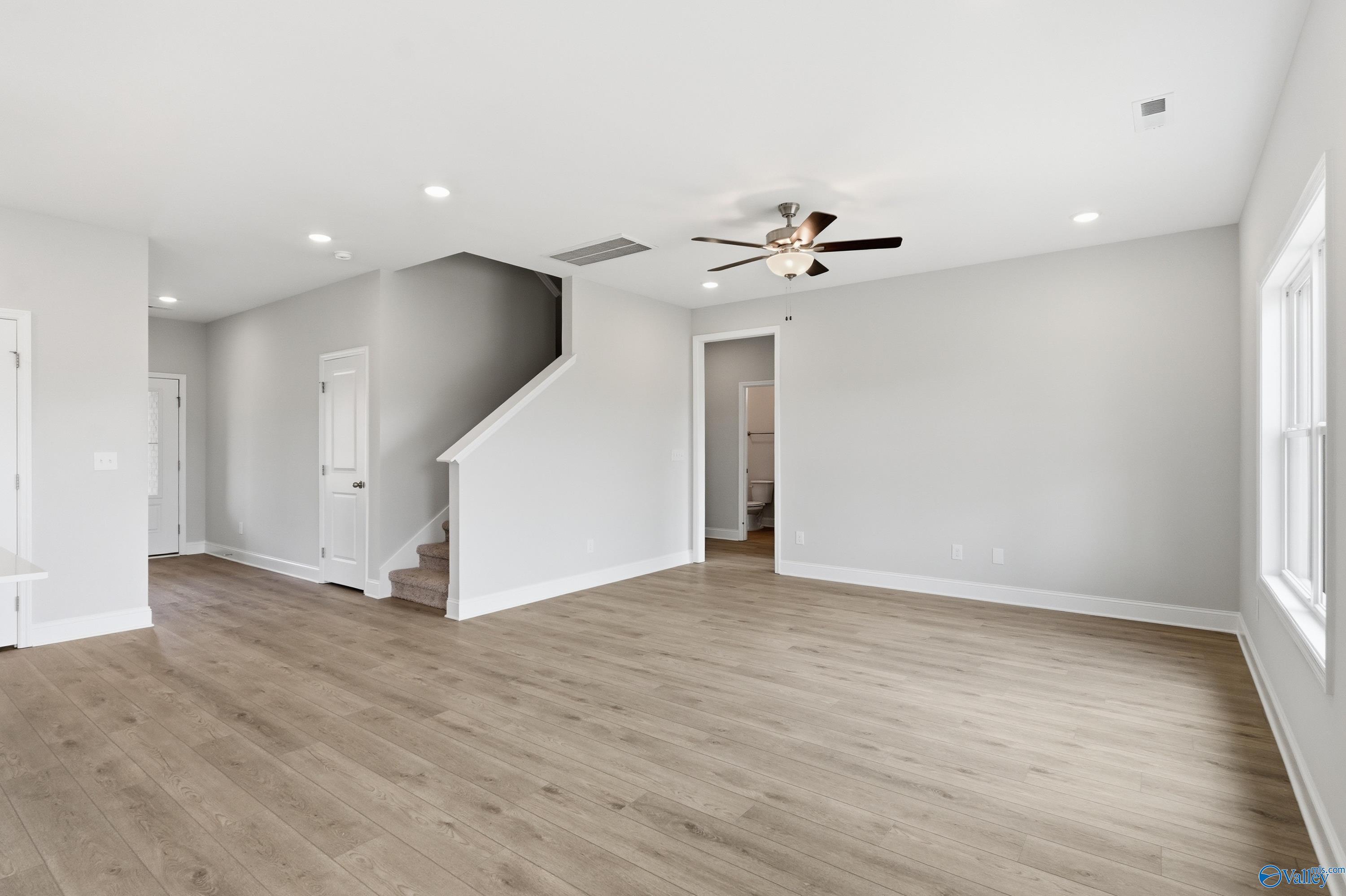 Bright two-story foyer with hardwood floors, ceiling fan, and staircase in Davidson Homes The Shelby B, New Market, Alabama