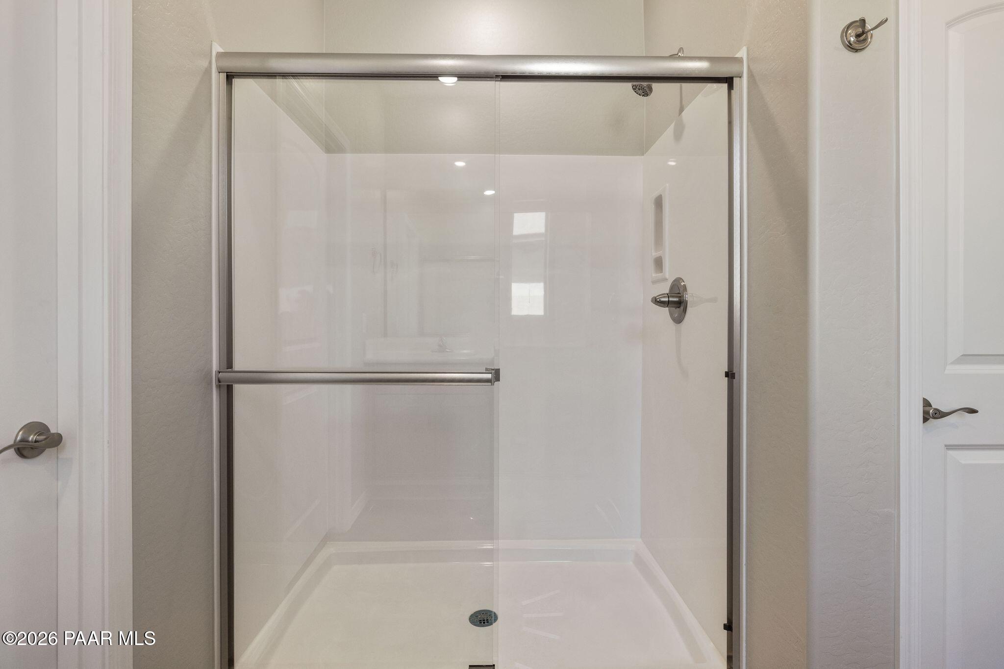 Modern frameless glass shower enclosure with white tile walls in master bath, Davidson Homes The Frontier A, Prescott Valley, Arizona