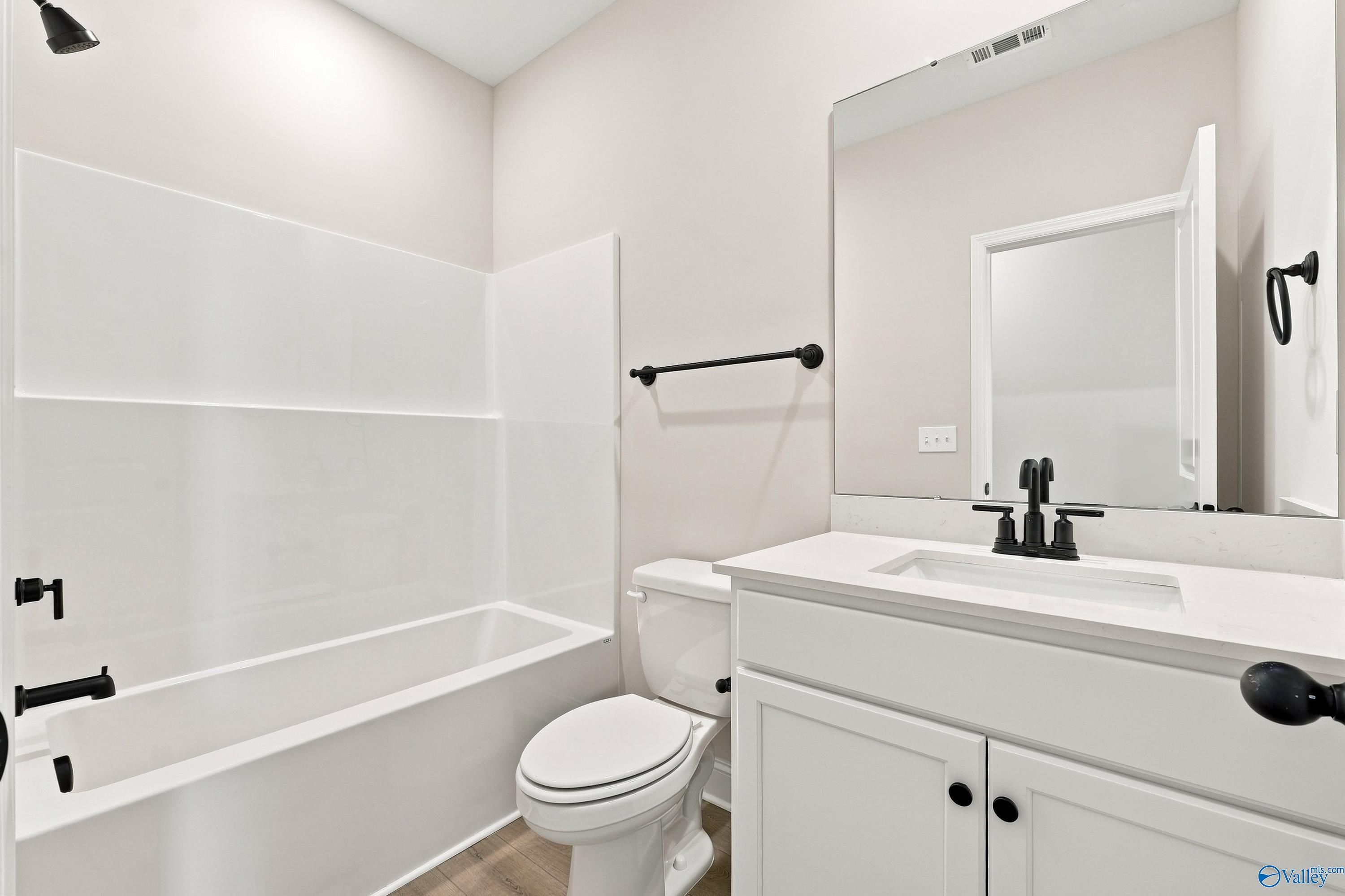 Modern bathroom with white vanity, matte black fixtures, and tub-shower combo in The Rockford B home in Kendall Downs.