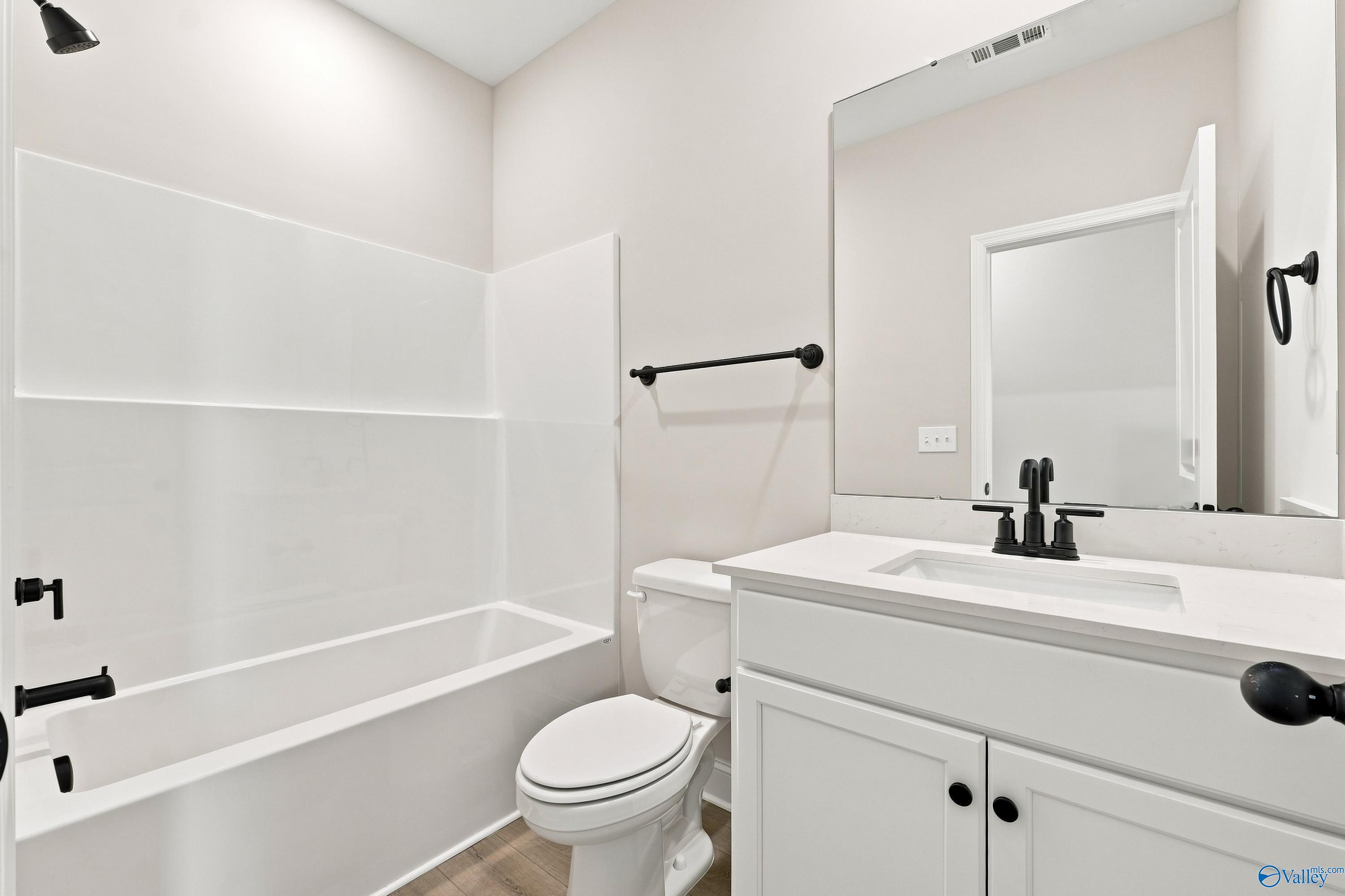 Modern bathroom with white vanity, matte black fixtures, and tub-shower combo in The Rockford B home in Kendall Downs.