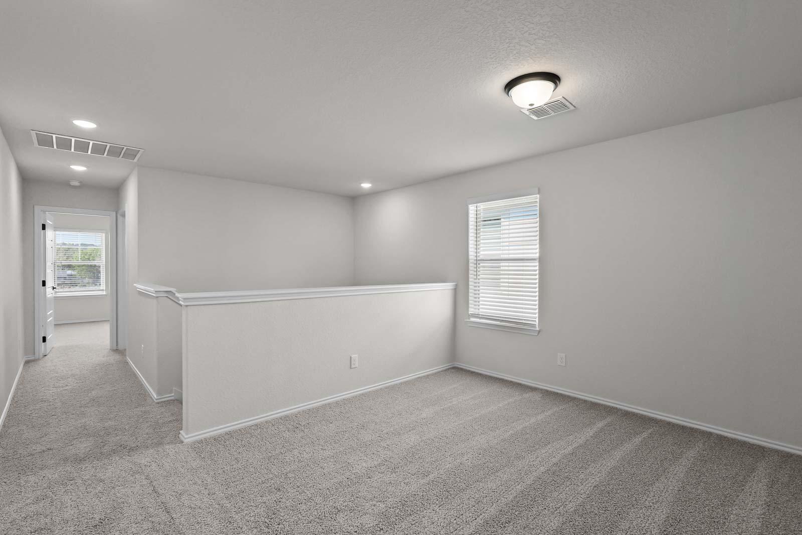 Spacious upstairs loft area in The Florence B home design featuring neutral carpet and abundant natural light.