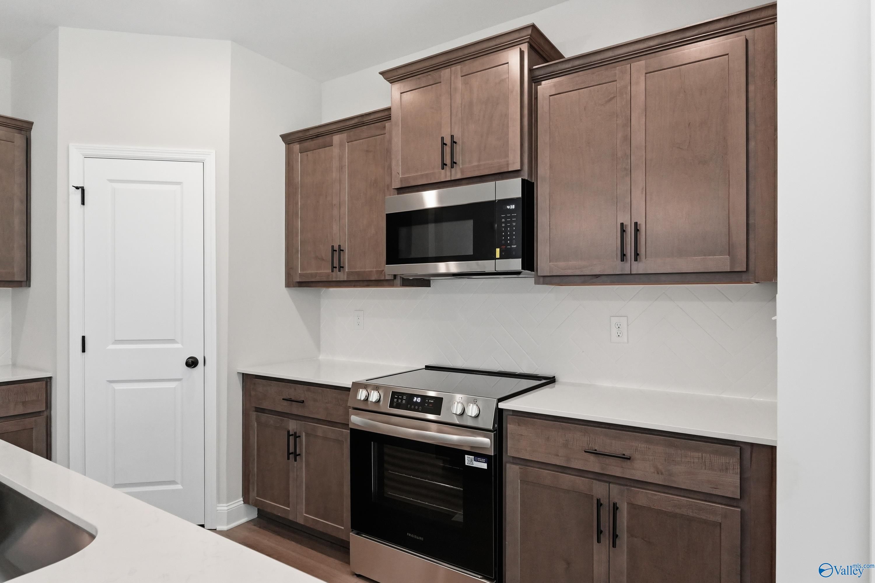 Modern kitchen featuring espresso shaker cabinets, white quartz counters, stainless steel range and microwave in Davidson Homes The Franklin, Huntsville AL