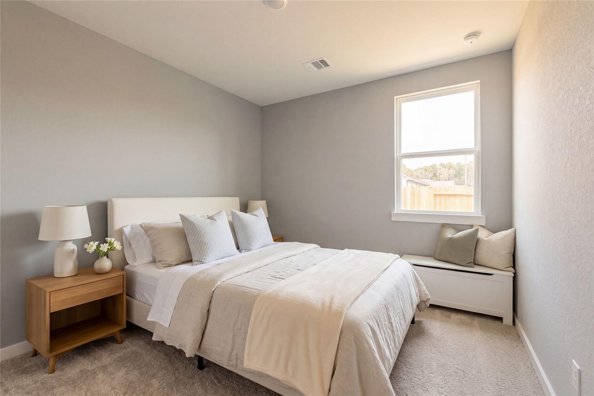 Cozy bedroom with white bed, gray walls, window bench and natural light in Davidson Homes The Frio G, Liberty Estates, Cleveland, Texas