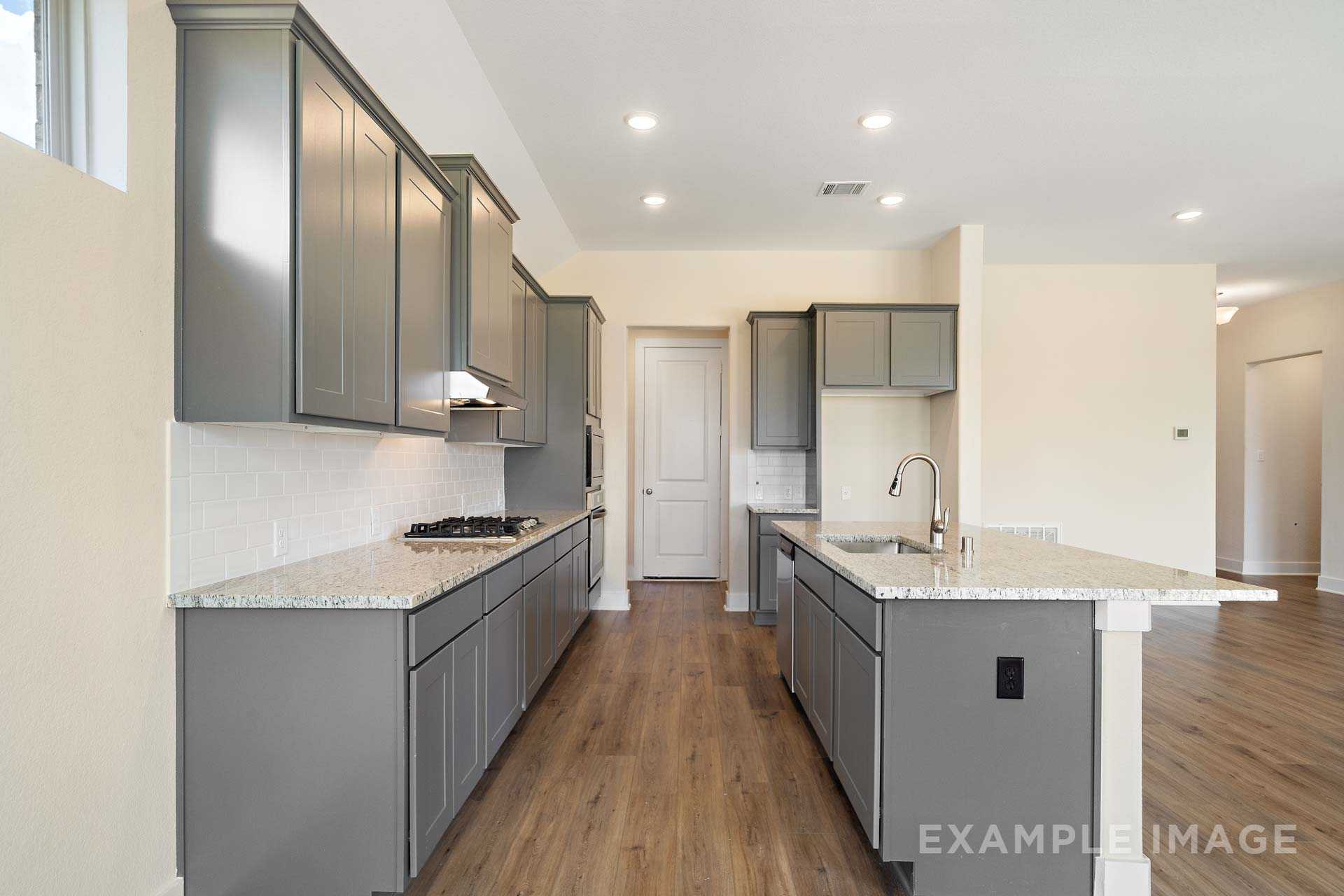Spacious kitchen in The Diana C by Davidson Homes with gray shaker cabinets, granite island, and open layout