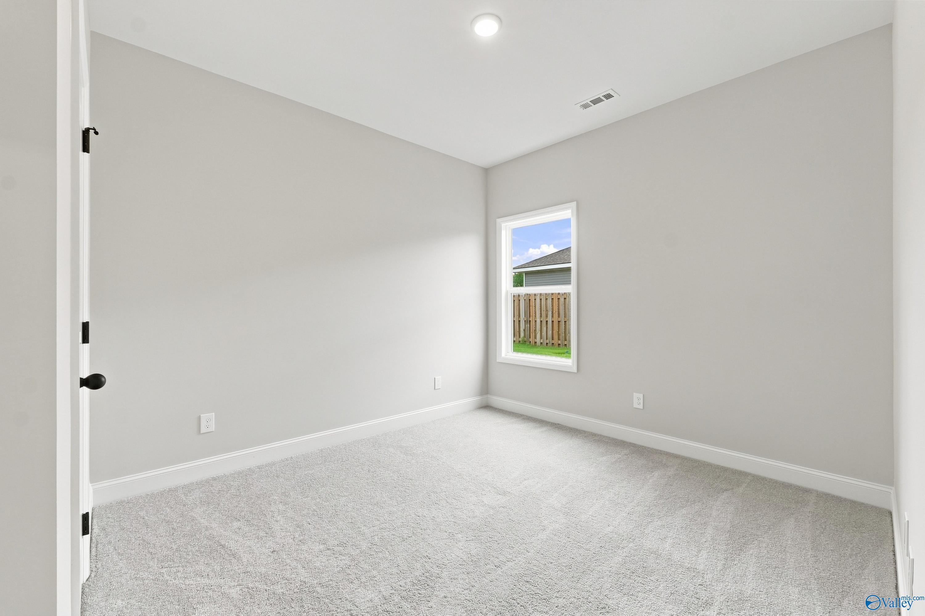 Bright, neutral-toned bedroom with plush carpet in The Asheville E floor plan by Davidson Homes in Hazel Green, Alabama.