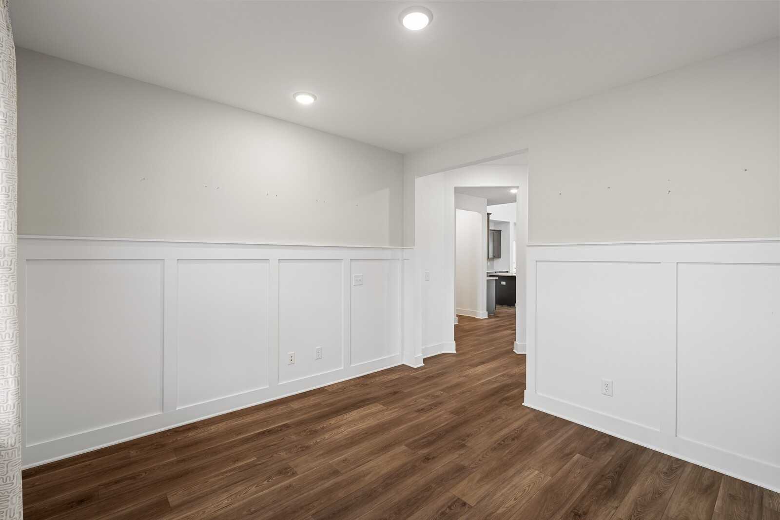 Bright bedroom with white wainscoting, beige walls, hardwood floors, and en-suite bathroom in Davidson Homes The Ridgeport, Gallatin, TN