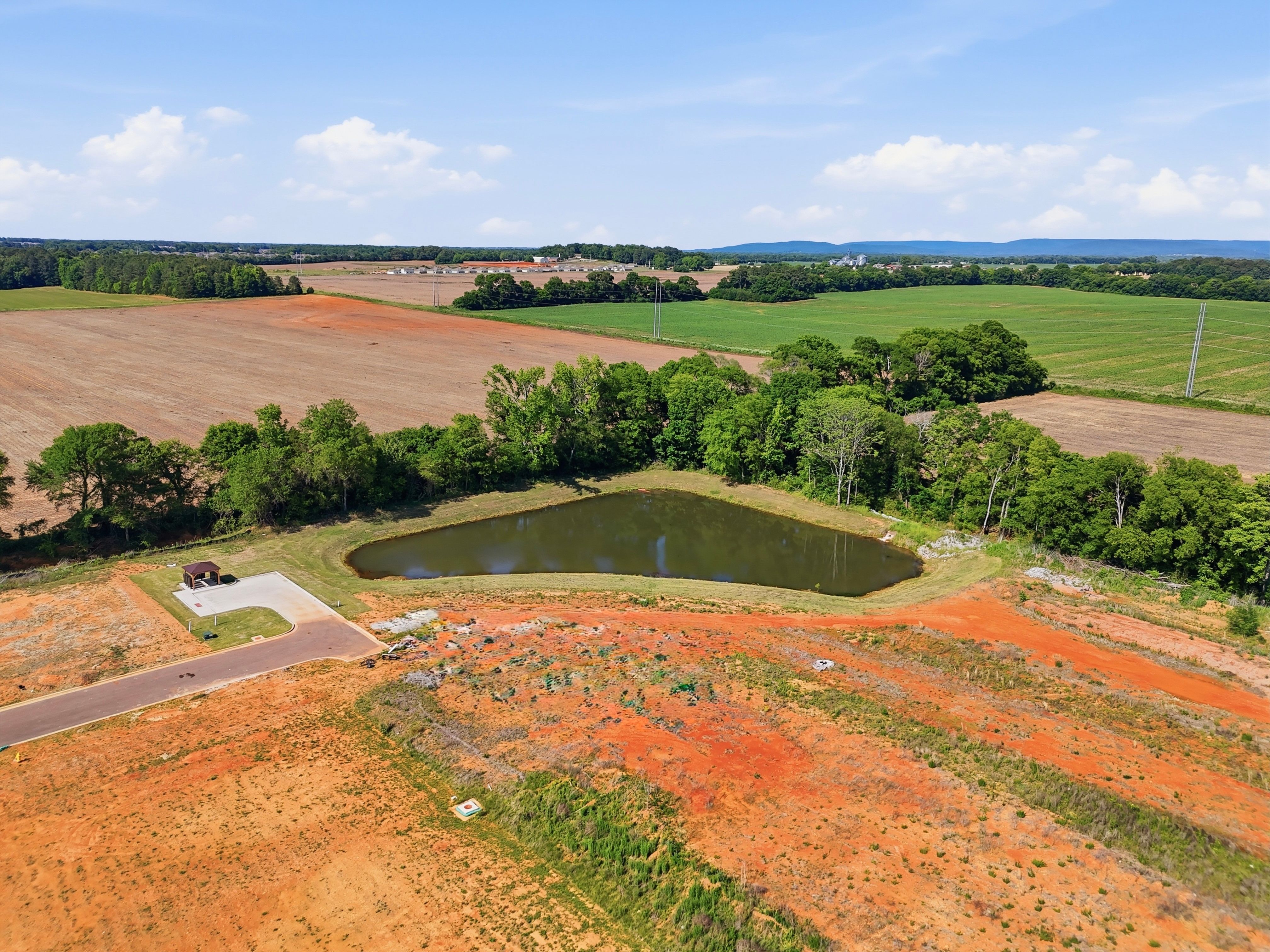 Aerial view of a scenic community pond at Lynn Meadows in Meridianville, AL, featuring surrounding green space.
