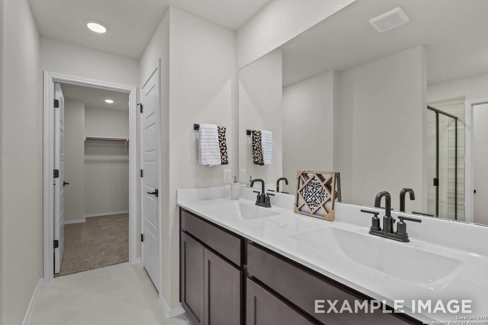 Elegant master bathroom with double vanity, dark cabinets, walk-in shower in Davidson Homes Trinity B, San Antonio