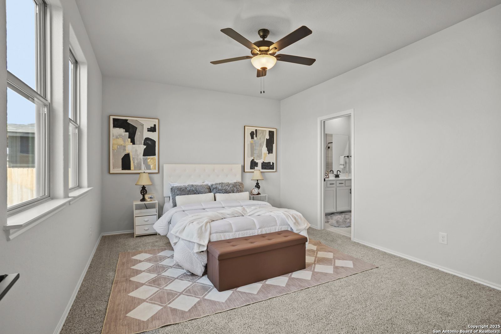 Elegant master bedroom with king bed, ceiling fan, abstract art, and en-suite bath in Davidson Homes The Douglas C, Seguin, Texas