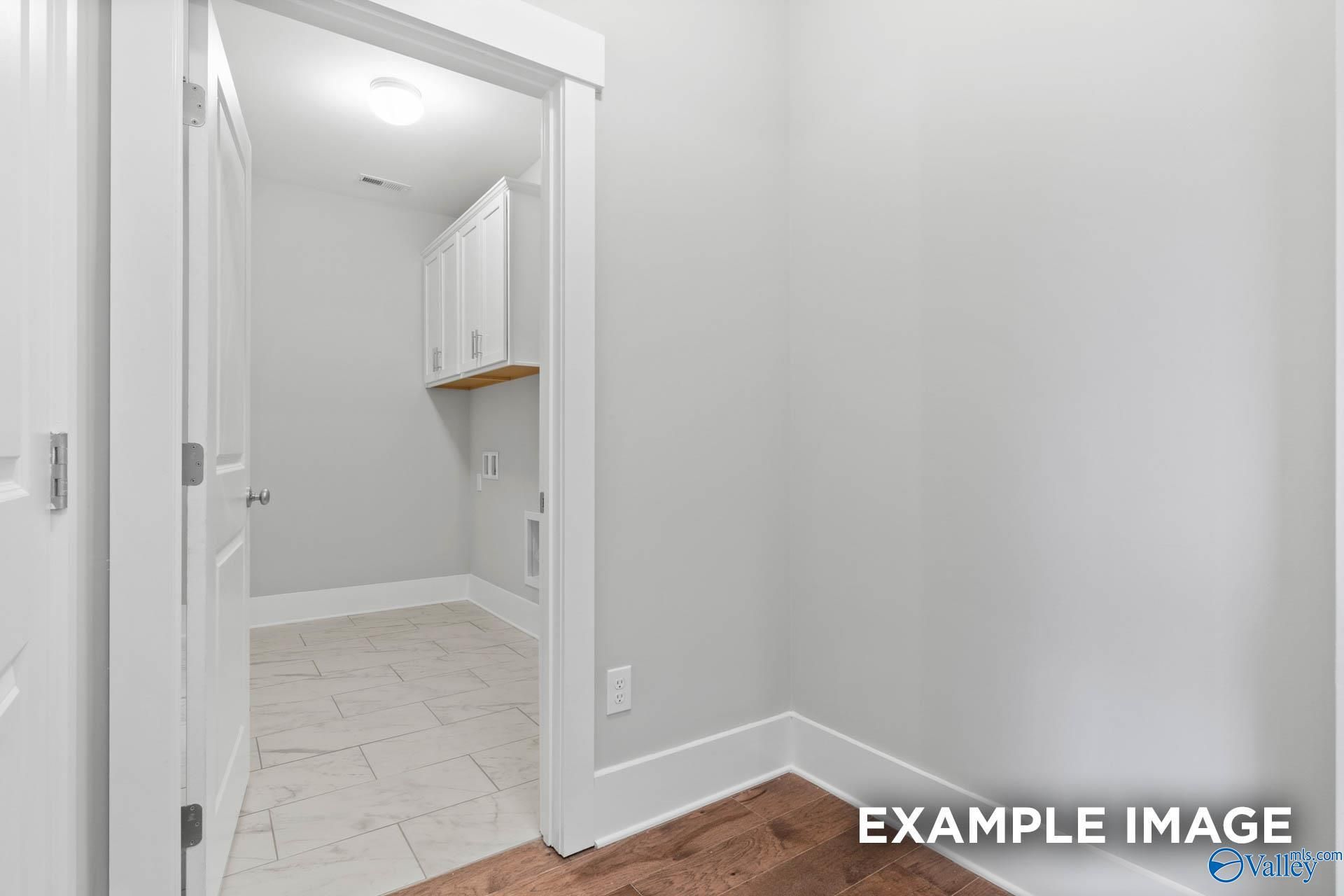 Bright laundry room with white cabinets, tiled floor, and utility space in Davidson Homes The Rockford, Meridianville, Alabama