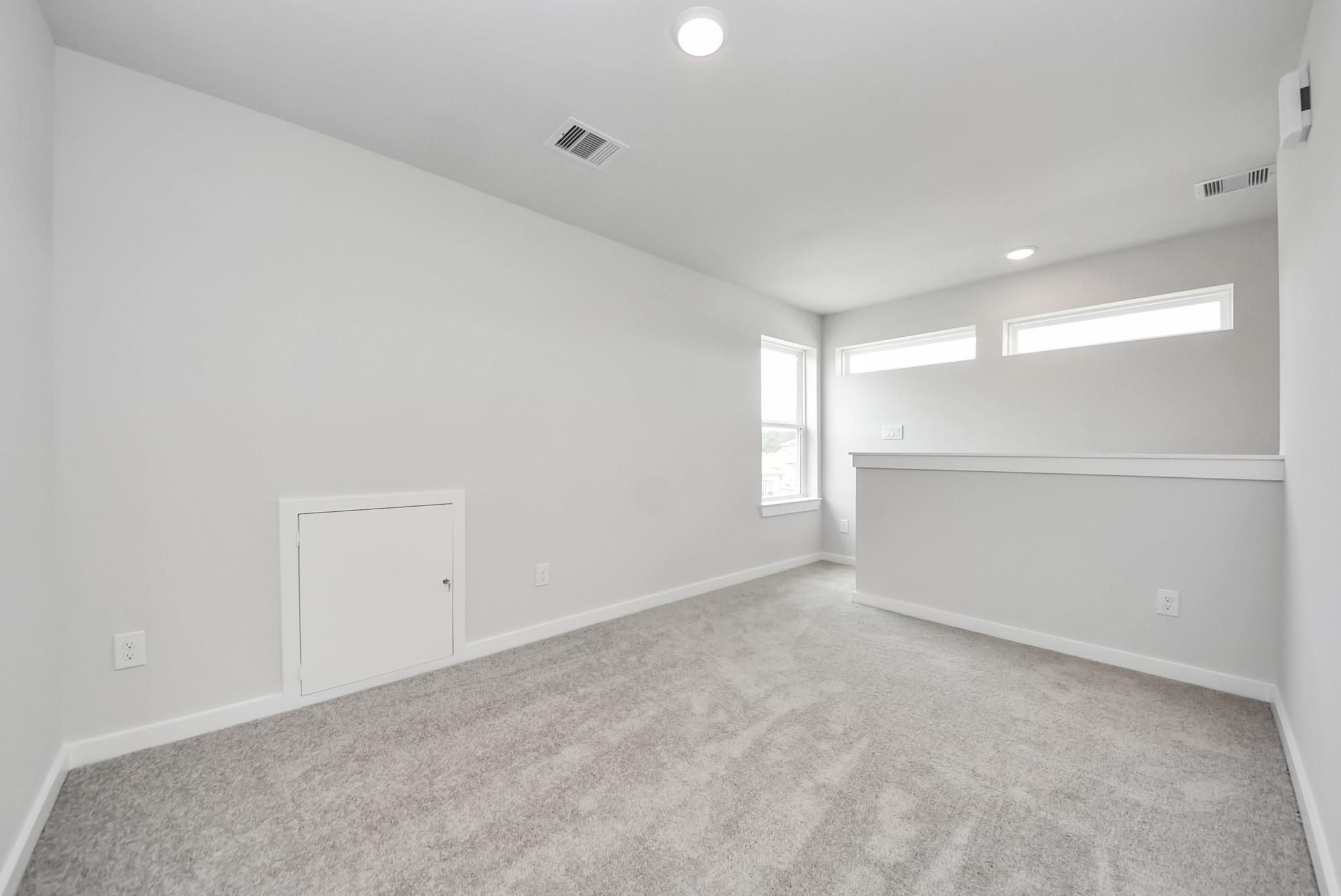 Spacious carpeted loft area with natural light in The Blanco E floor plan at The Villages at WestPointe, Dayton, Texas.