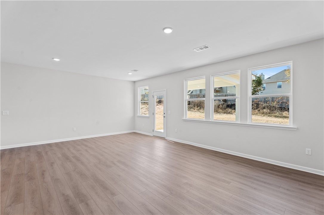 Bright open living room with hardwood floors, large windows, and gray walls in The Luna B floor plan, Opelika, Alabama