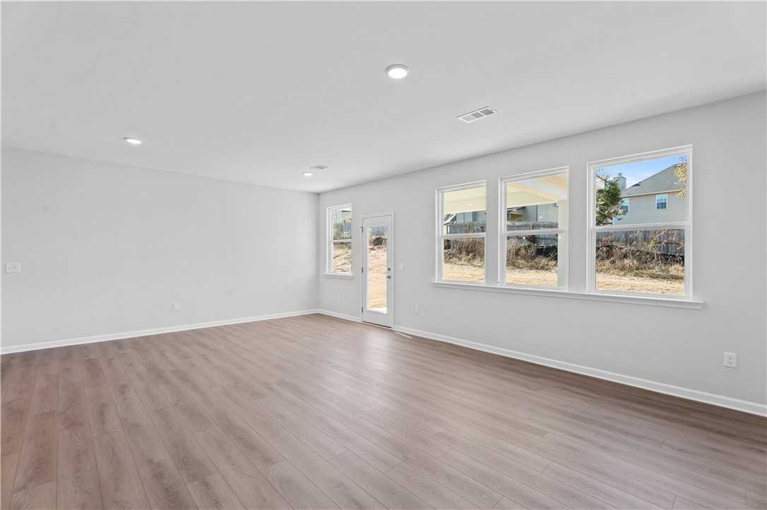 Bright open living room with hardwood floors, large windows, and gray walls in The Luna B floor plan, Opelika, Alabama