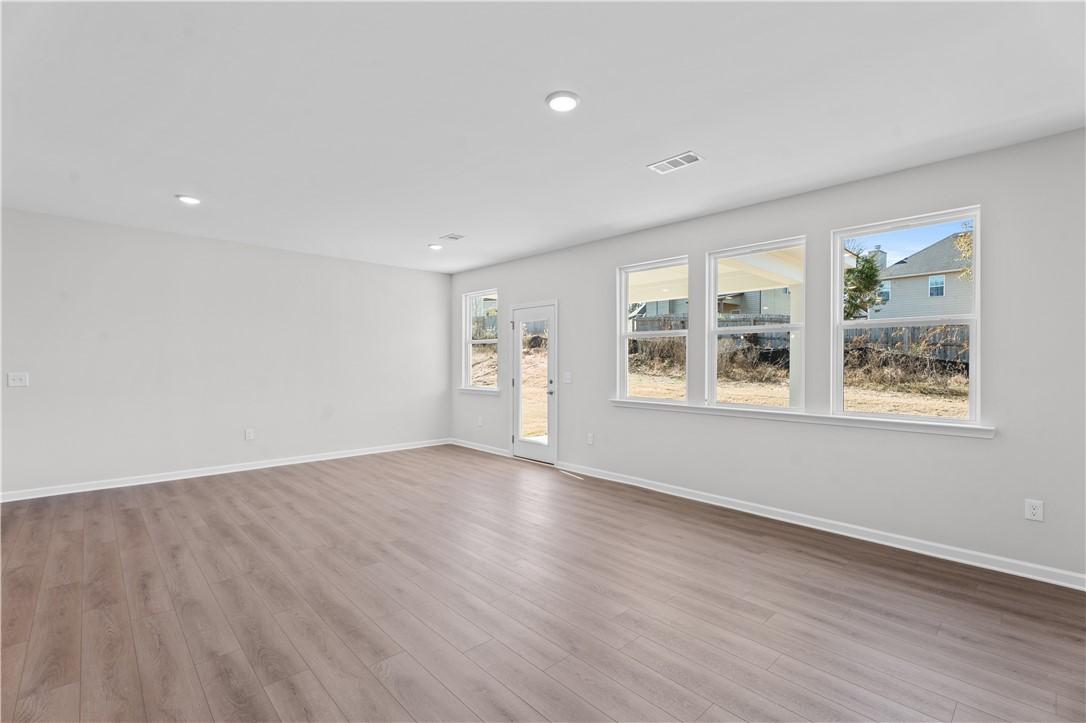 Bright open living room with hardwood floors, large windows, and gray walls in The Luna B floor plan, Opelika, Alabama
