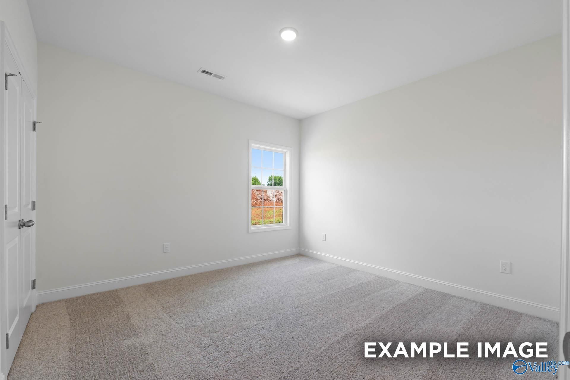 Bright empty bedroom with beige carpet, white walls, and large window in The Oxford 4-bedroom home, Riverton Preserve, Huntsville, Alabama