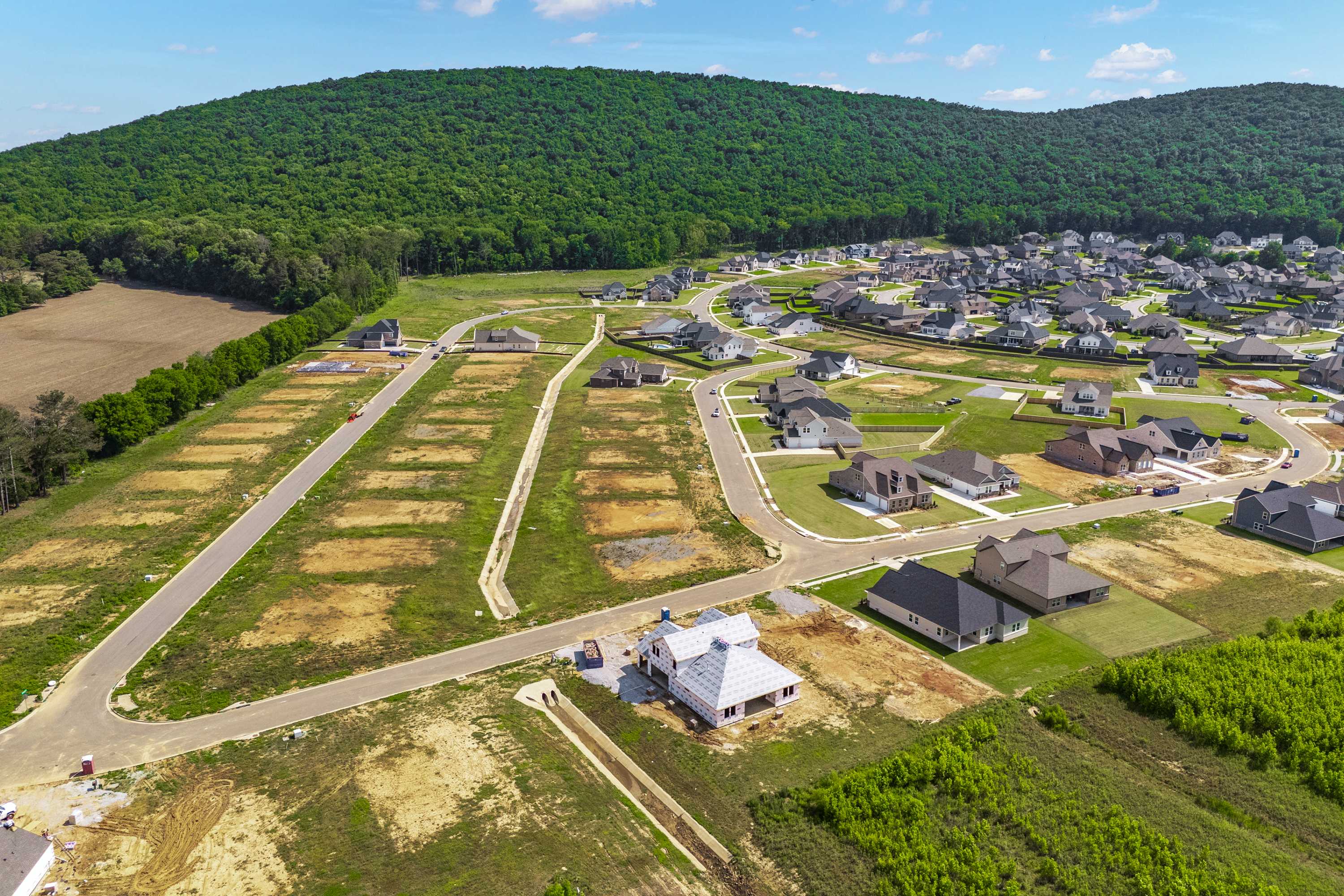 Aerial view of new homes and lots at The Meadows at Hampton Cove in Owens Cross Roads AL amid green hills and forests