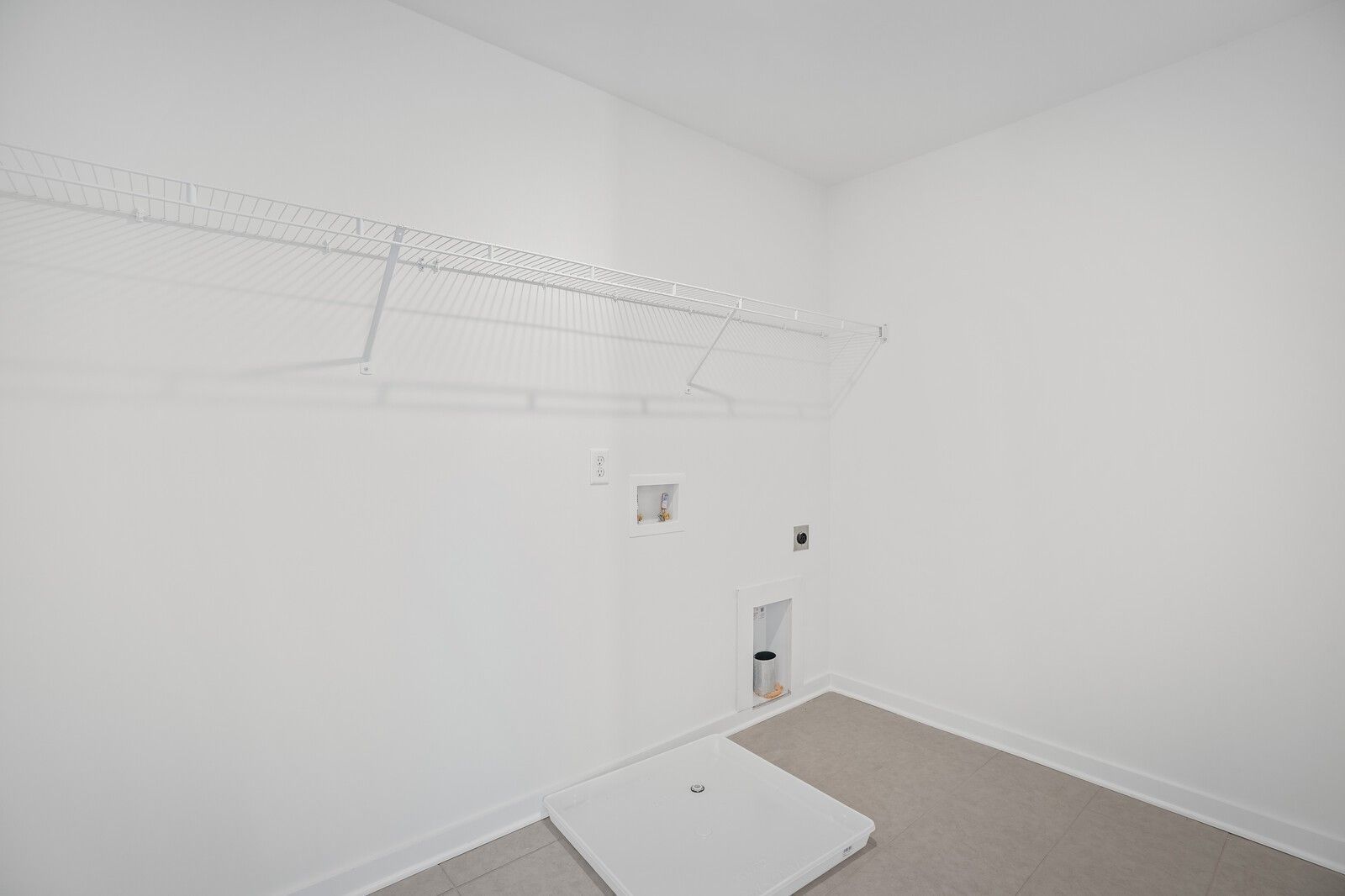 Spacious white laundry room with wire shelving, hanging rods, and washer-dryer hookups in The Willow C home, Gallatin, TN
