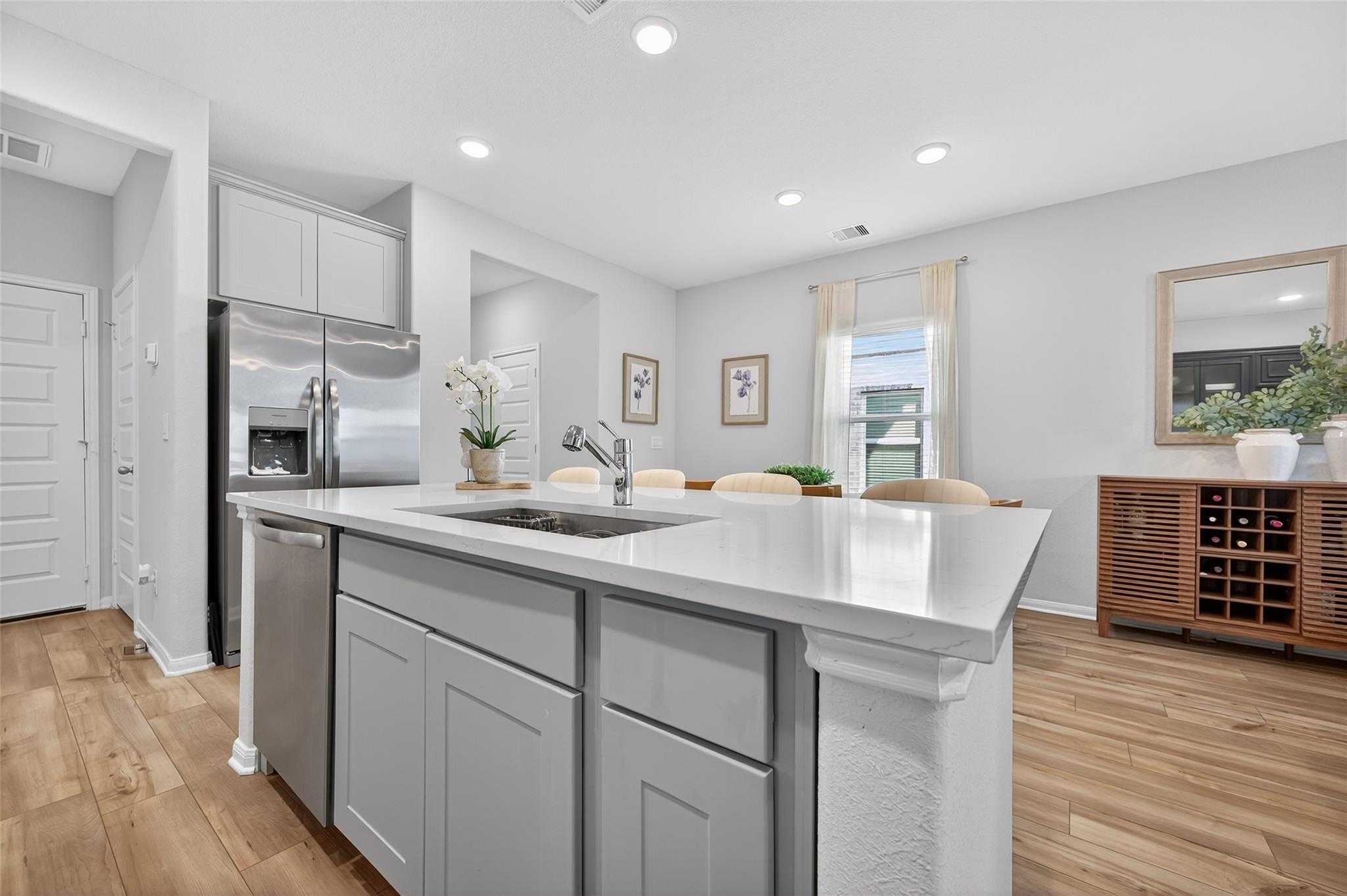 Modern open-concept kitchen with stainless appliances, white quartz island, and dining nook in 5-bedroom The Brazos E home, Magnolia, TX