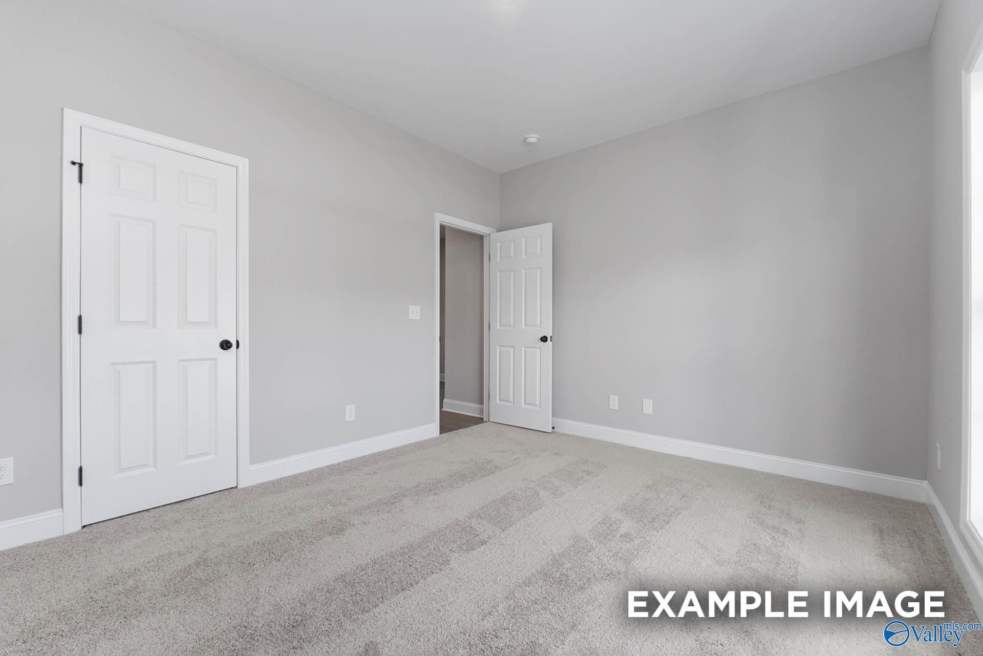 Bright secondary bedroom with gray walls, carpet flooring, and open bathroom door in The Daphne D, Meridianville, Alabama
