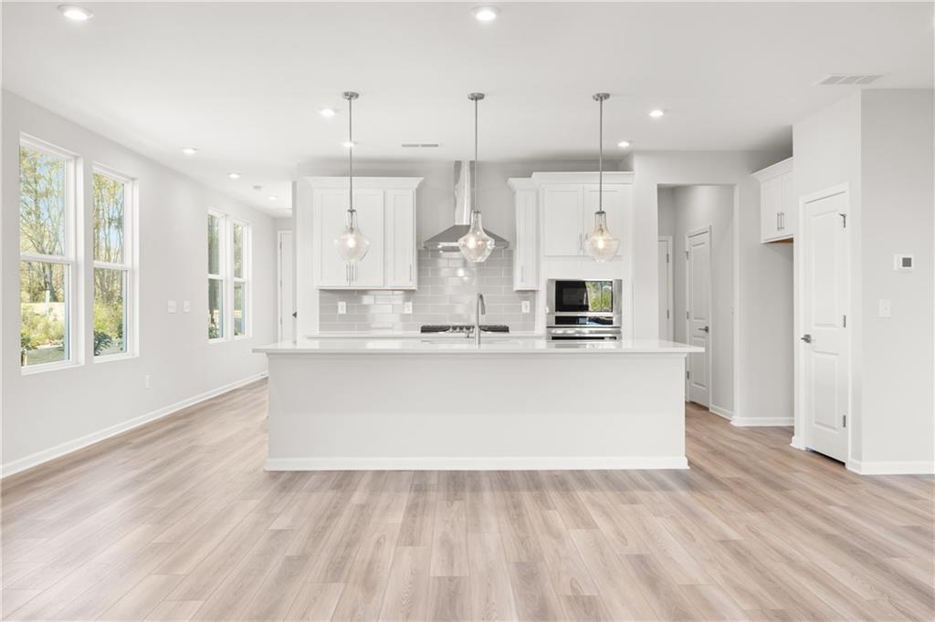 Modern white kitchen featuring large island, subway tile backsplash, stainless appliances in Davidson Homes The Cary A, Winder GA