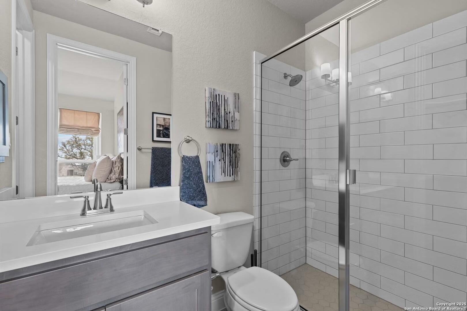 Modern master bathroom featuring double vanity, frameless glass shower, subway tile walls in The Garner B by Davidson Homes, Castroville, Texas