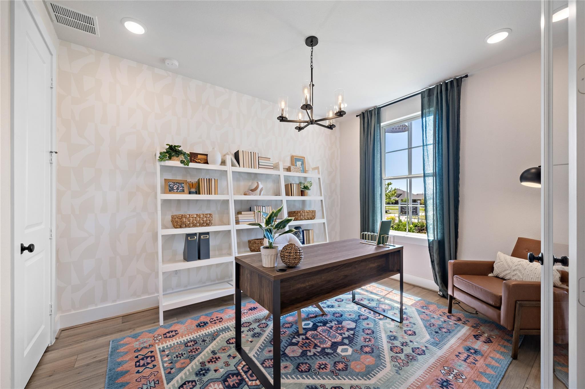 Bright home office with wood desk, ladder shelving, and patterned rug in Davidson Homes The Edward A, Lago Mar, Texas City