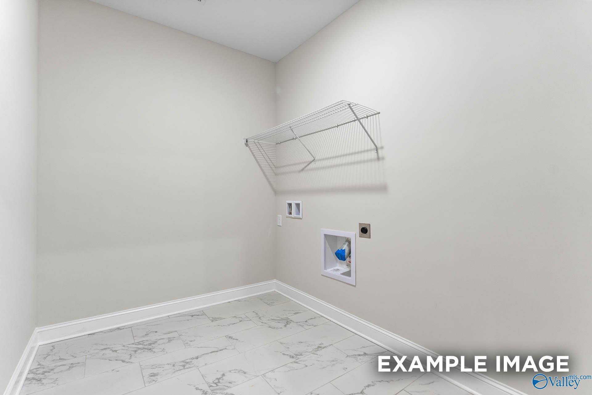 Bright laundry room with wire shelving, washer-dryer hookups, and marble-look tile floor in The Finleigh home, Huntsville, AL