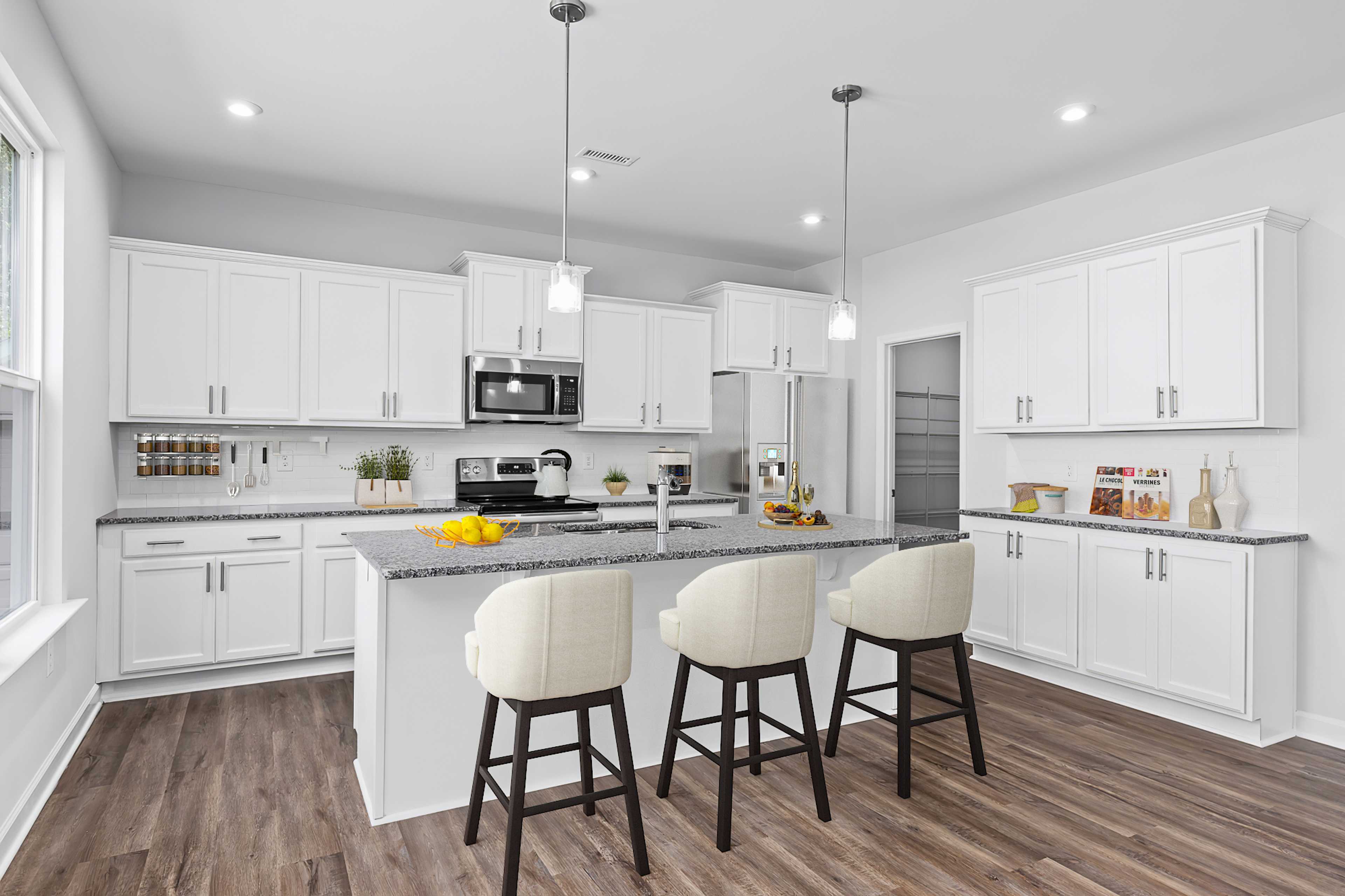 Spacious white kitchen at Enclave at Belmont in Belmont NC with large island, upholstered bar stools, hardwood floors, and pendant lights