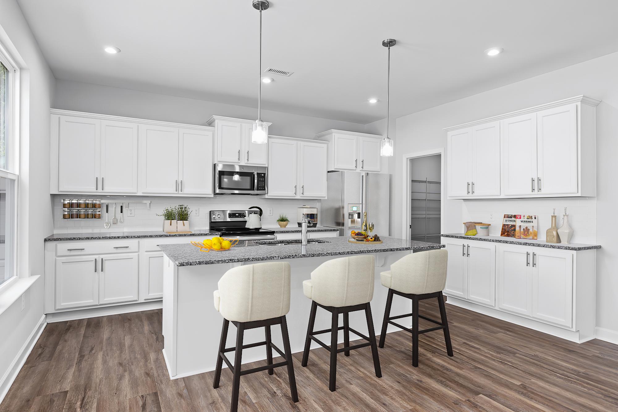 Spacious white kitchen at Enclave at Belmont in Belmont NC with large island, upholstered bar stools, hardwood floors, and pendant lights