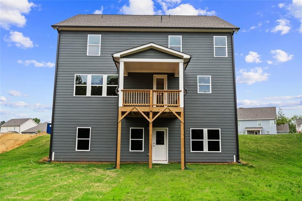 Two-story gray Davidson Homes Hickory B with wooden upper deck, covered patio, and grassy backyard in Wehunt Meadows, Hoschton, GA