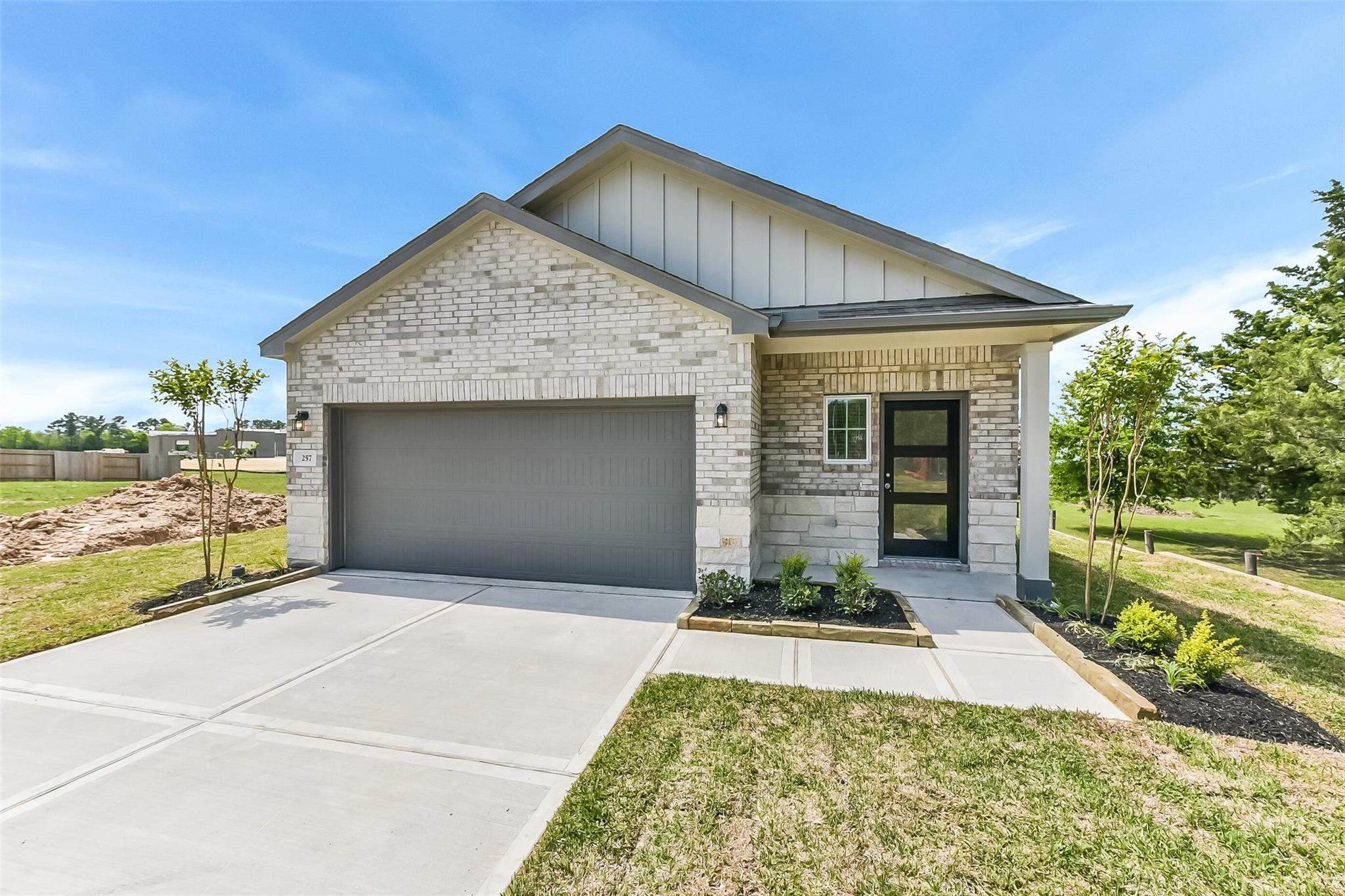 Modern white brick single-story home with 2-car garage, landscaped yard, and driveway in Windmill Estates, Magnolia, Texas - Davidson Homes The Frio G