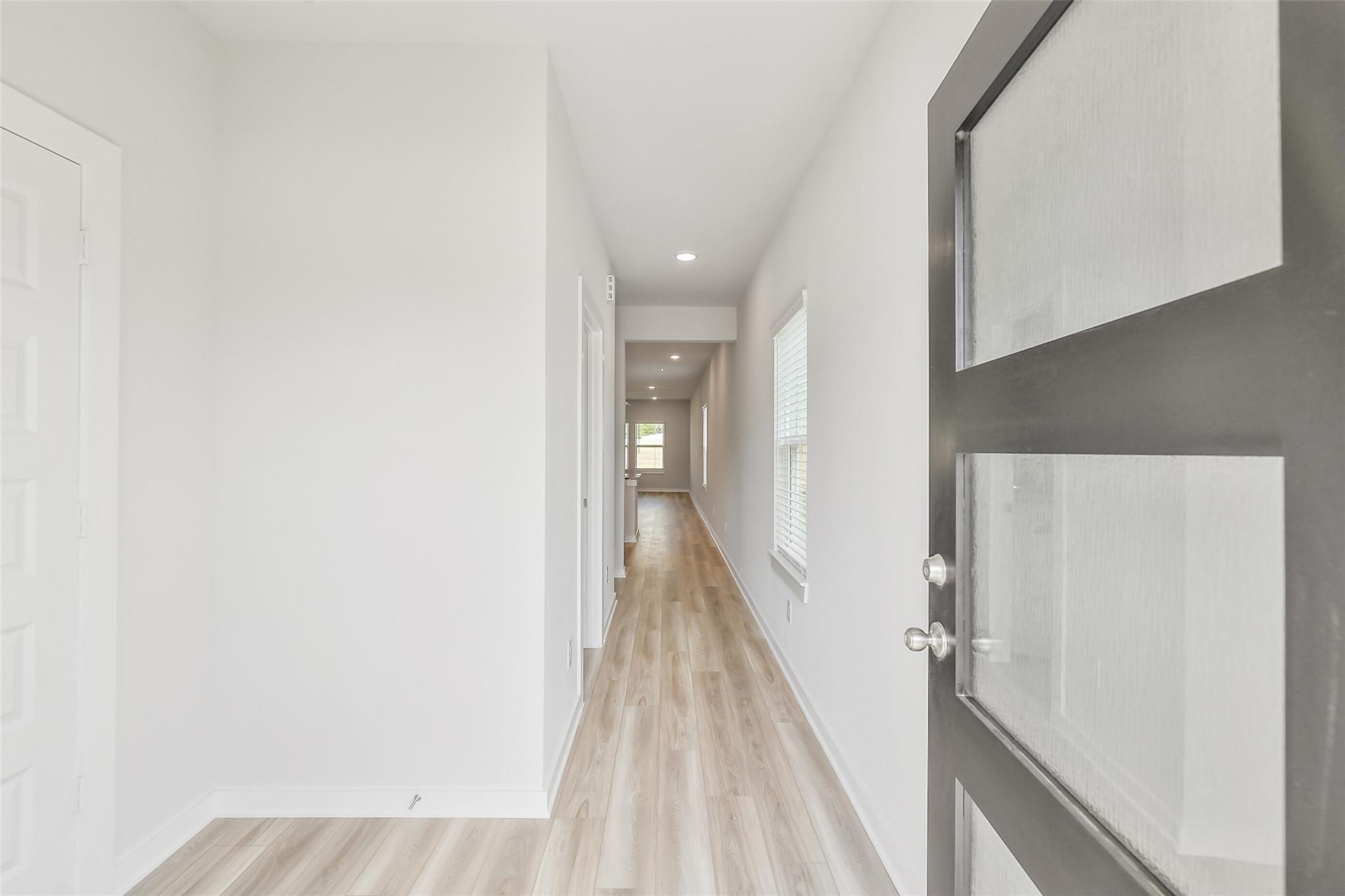 Bright hallway with light wood floors, white walls, side doors, and frosted glass entry in Davidson Homes San Marcos E, Conroe, TX