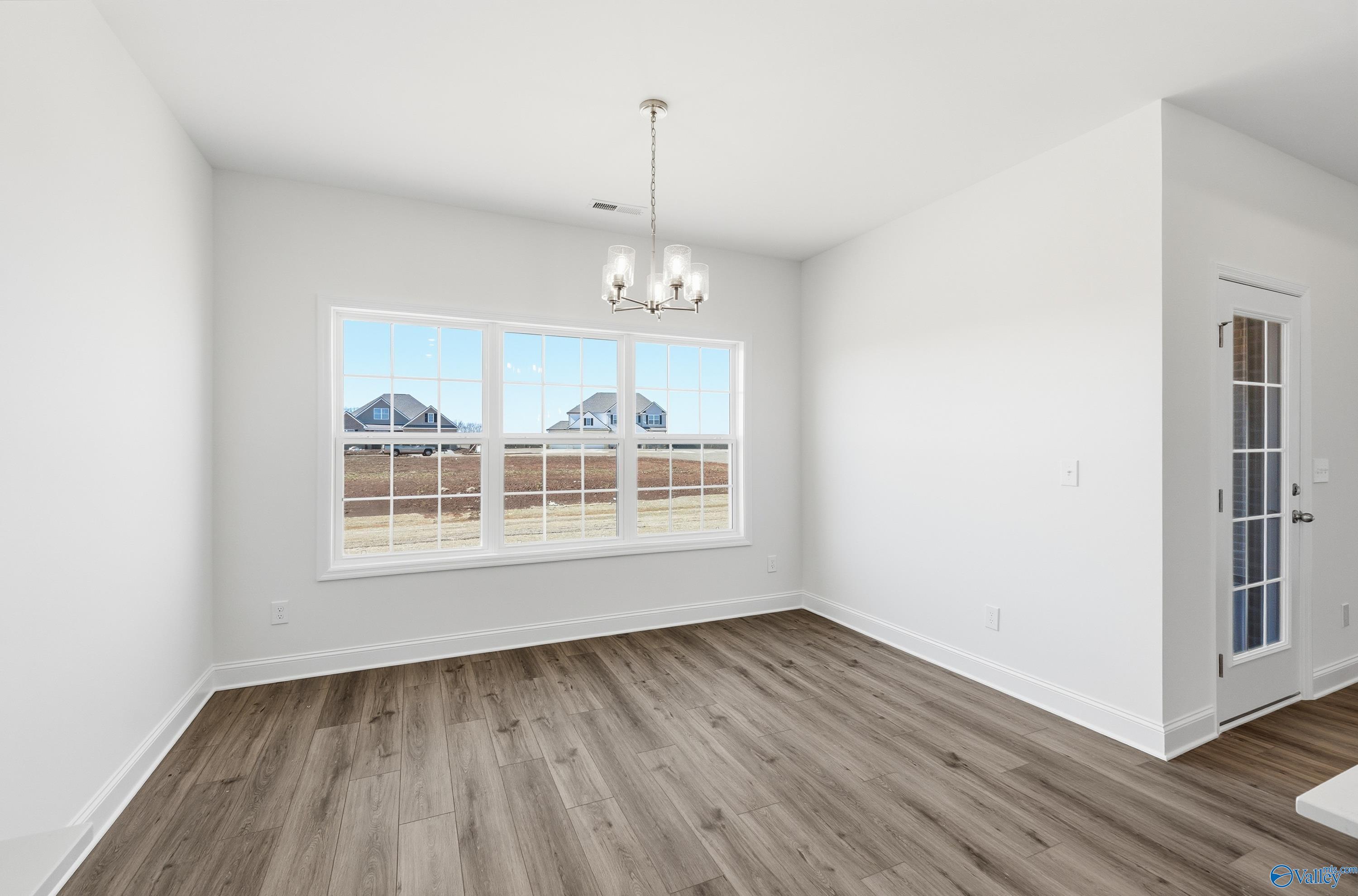Bright dining room with hardwood floors, chandelier, and large windows in The Montgomery 3-bedroom home, Pikes Ridge, Meridianville