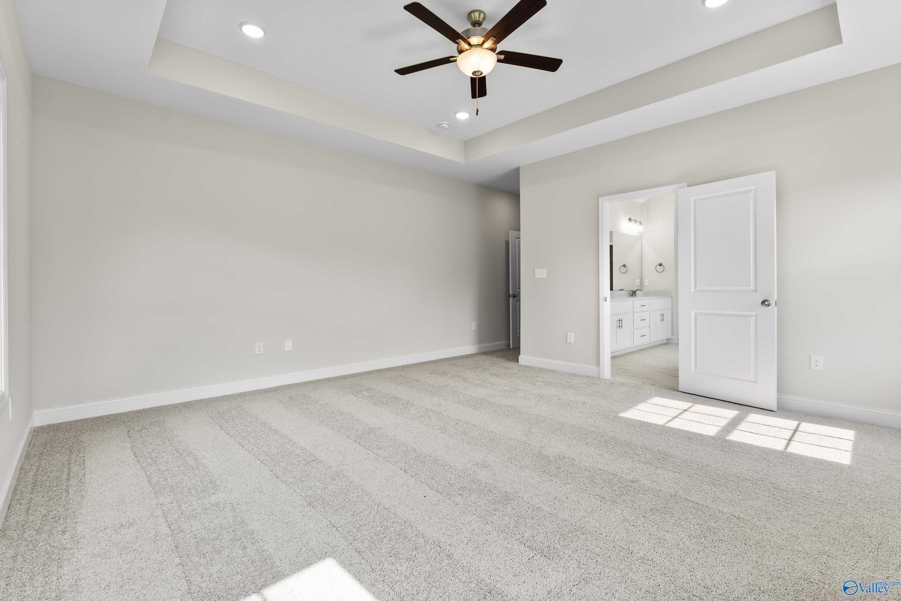 Spacious bedroom with ceiling fan, recessed lights, and en-suite bathroom door in Davidson Homes The Finleigh, Toney, Alabama